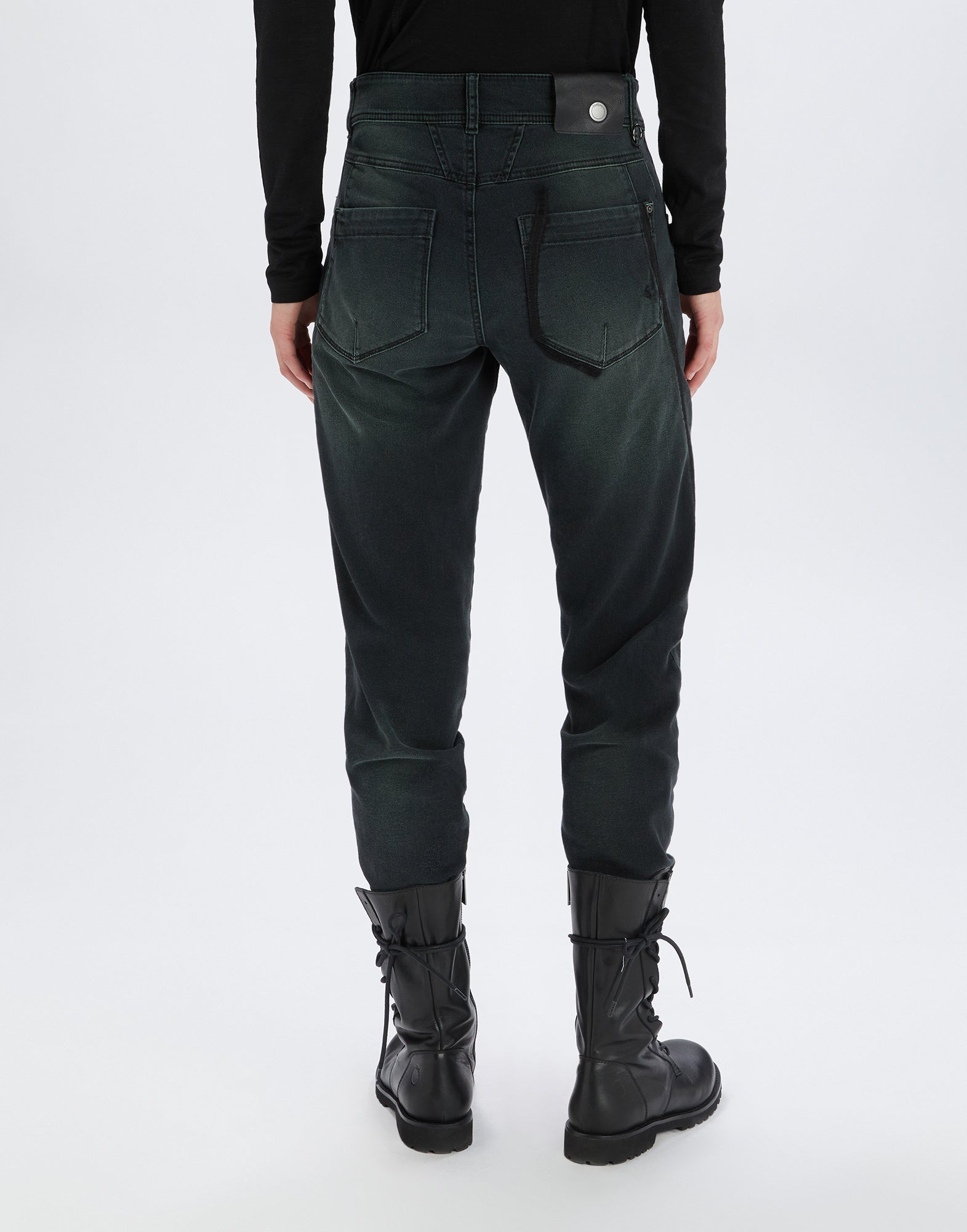 Rückansicht der Jeans HAPPLY, getragen von einer Person mit schwarzen Stiefeln. Sichtbare Gesäßtaschen, kontrastierende dunkle Einsätze und markante Nahtdetails.