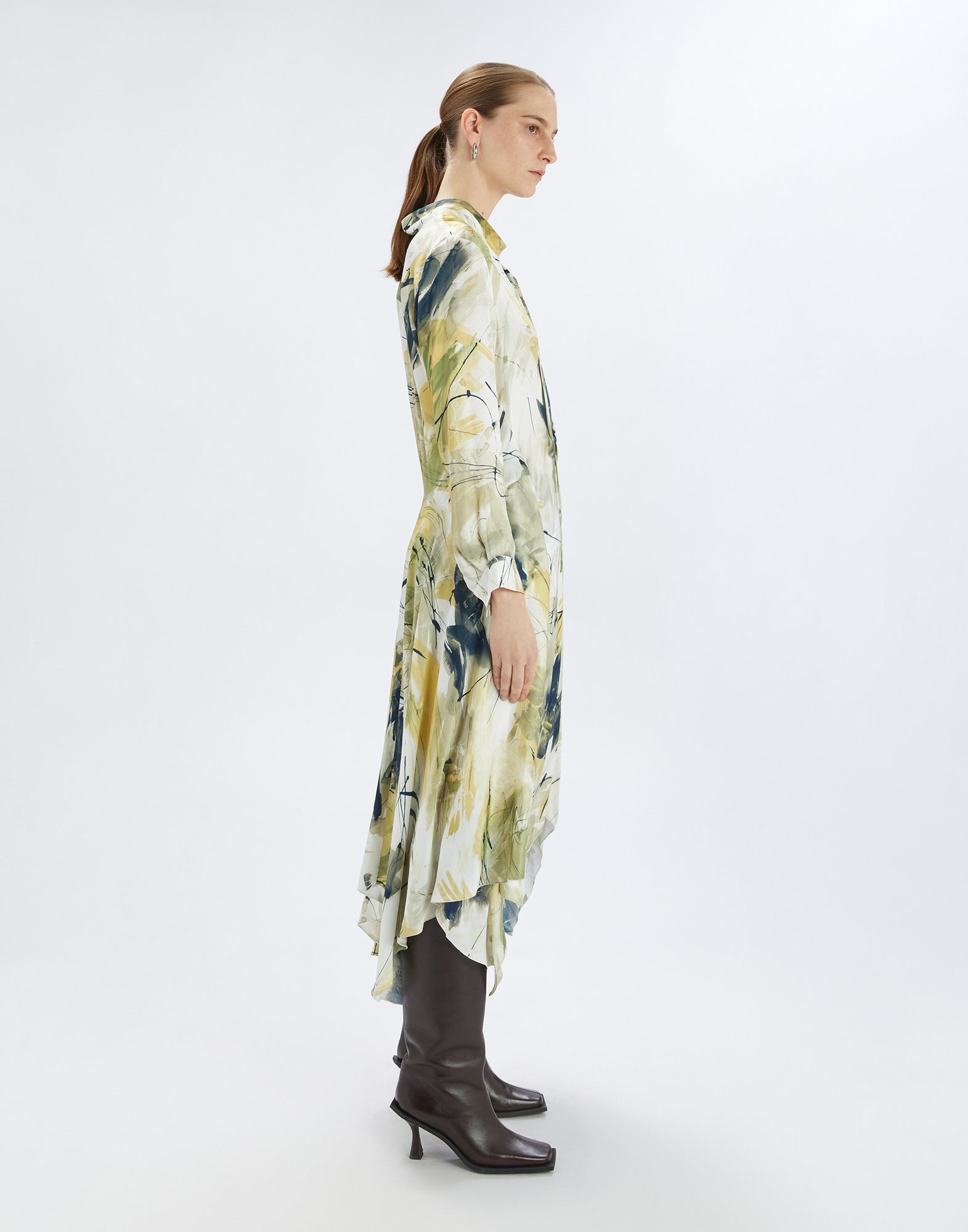Seitenansicht des FILO Kleides mit abstraktem Muster in Gelb- und Grüntönen, unregelmäßigem Saum, Stehkragen, langen Ärmeln und fließender Silhouette.