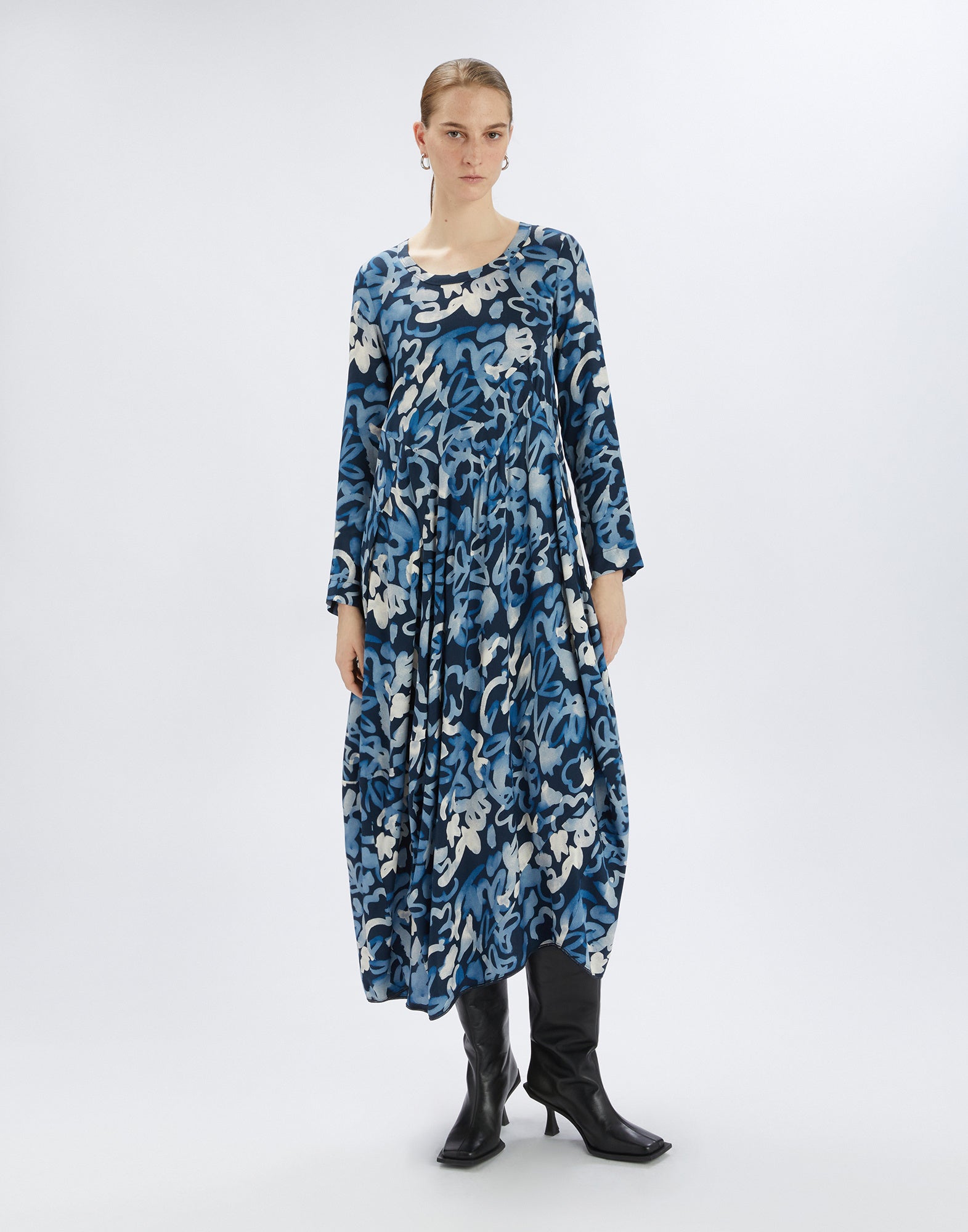 Frontalansicht: Eine Frau trägt das strukturierte Kleid AWAKENING mit leuchtendem Elektroblau-Druck, ballonartigem Rock und figurbetontem Oberteil in moderner Silhouette.