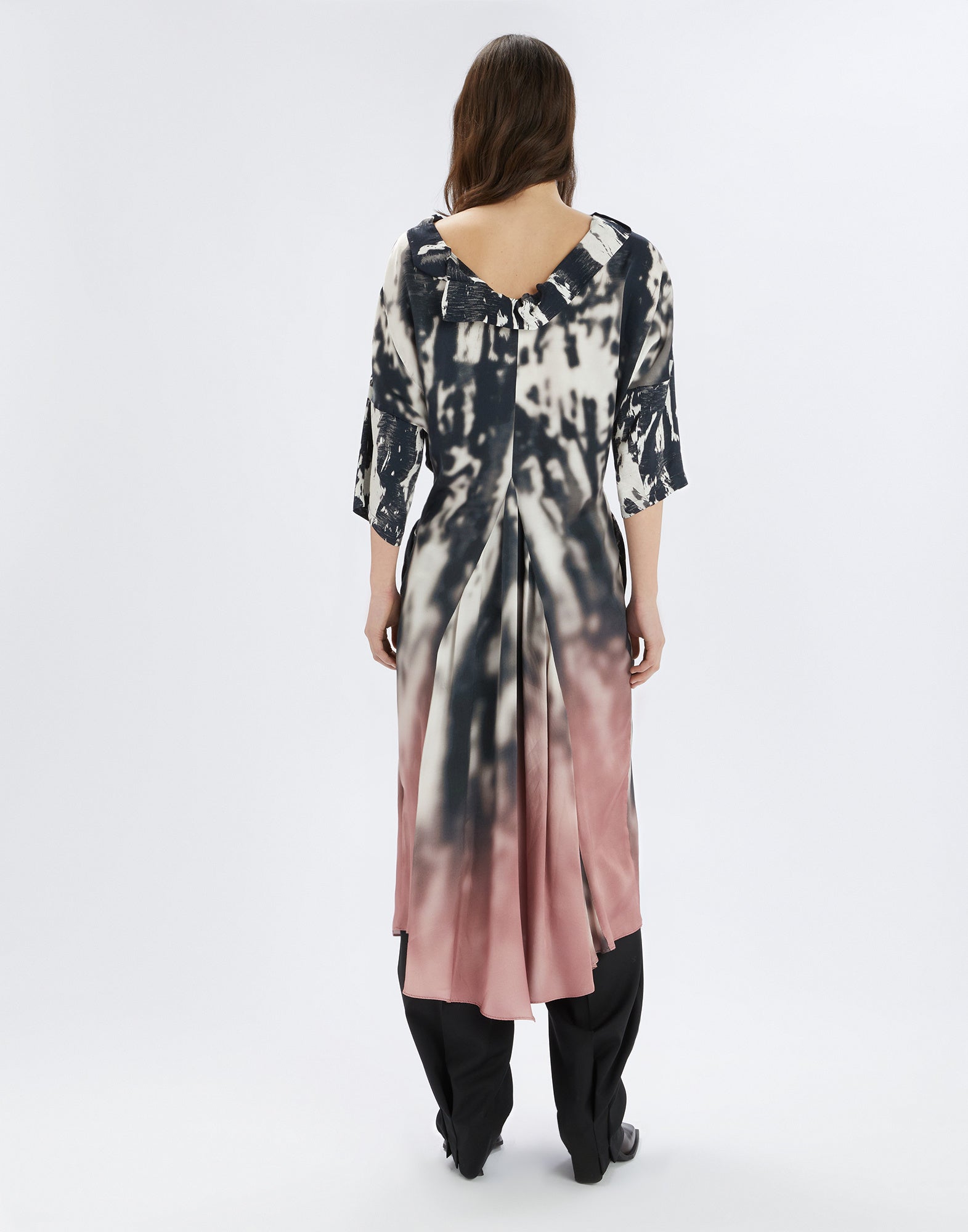 Rückansicht des STOP PRESS Kleides mit abstraktem Schwarz-Weiß-Rose-Pink Druck, asymmetrischem Saum, Bootcut-Kragen und dreiviertel langen Ärmeln, getragen von einer Frau.