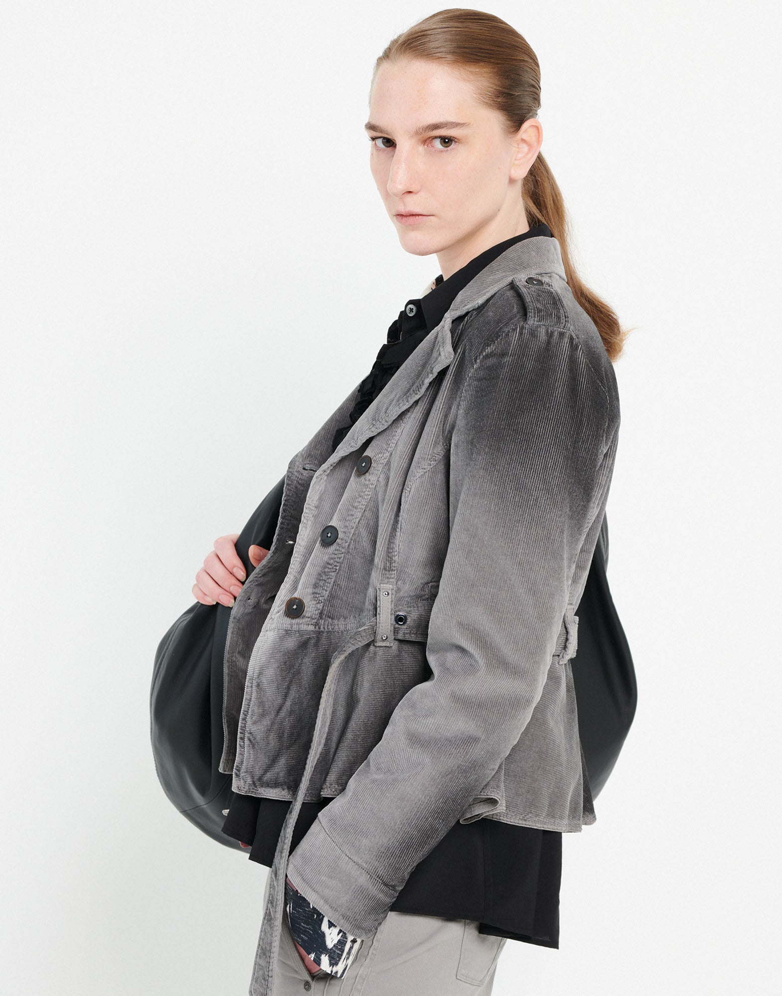 Side view: person wears GIG Corduroy Biker Jacket in grey with belt, wide lapels, double-breasted front, and shoulder epaulettes. Visible stitching and cropped fit.