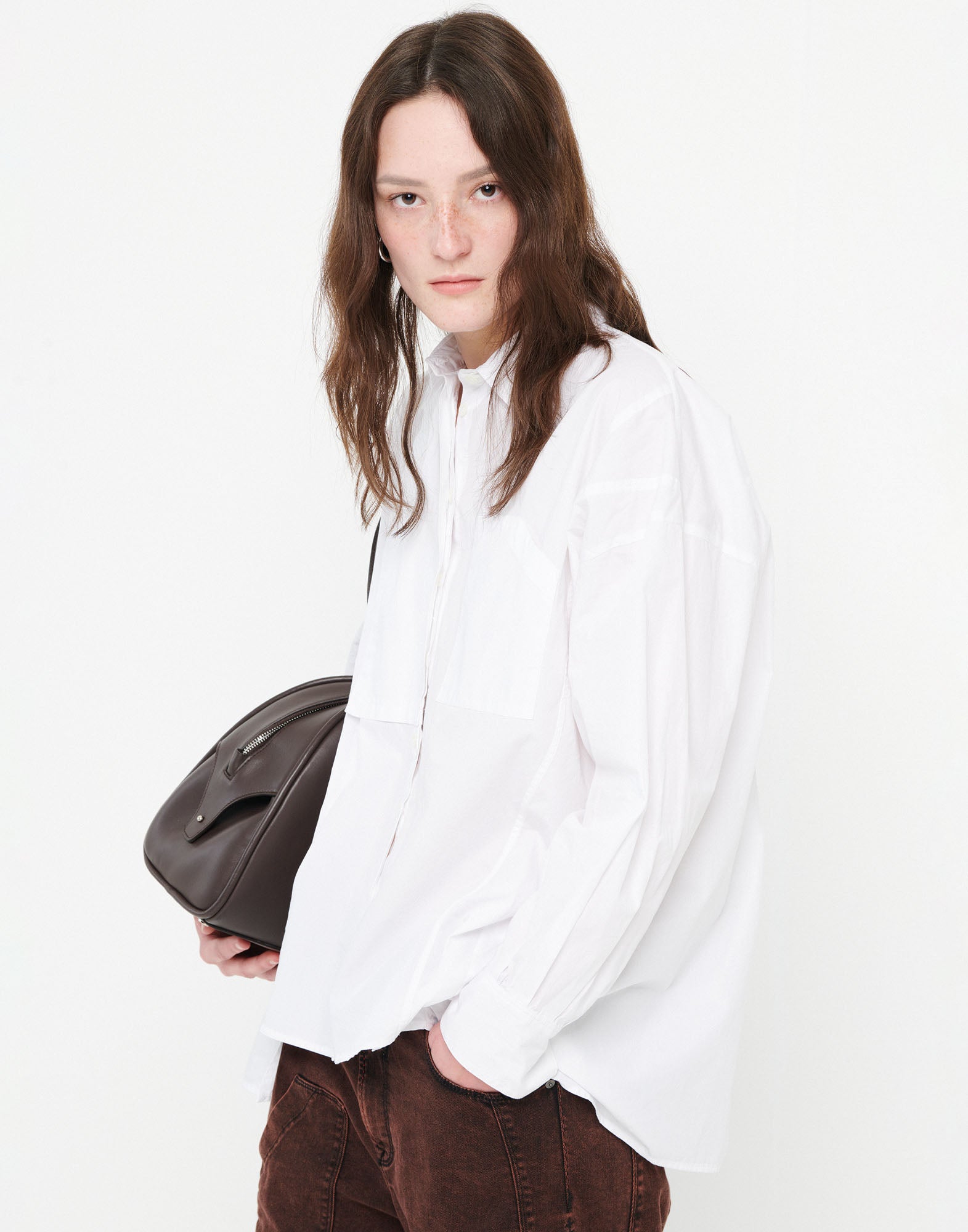 Front view: A person wears the DEADLINE shirt in white with a loose, fluid fit, turn-down collar, and asymmetric rounded hem. Light and casually styled.