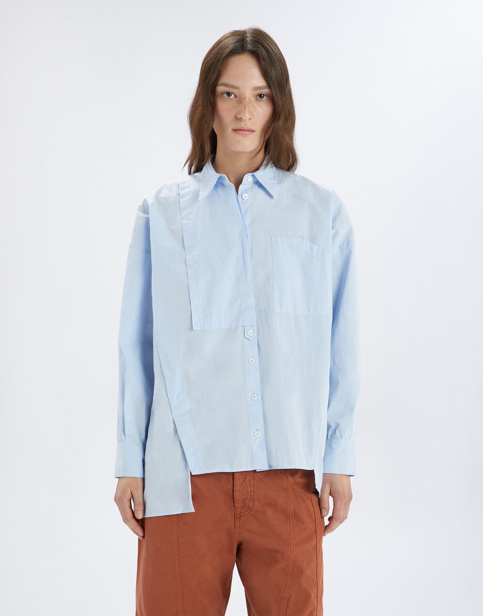 Front view: A person wears the DEADLINE shirt in light blue with an asymmetric front, chest pocket, long sleeves, and button placket.