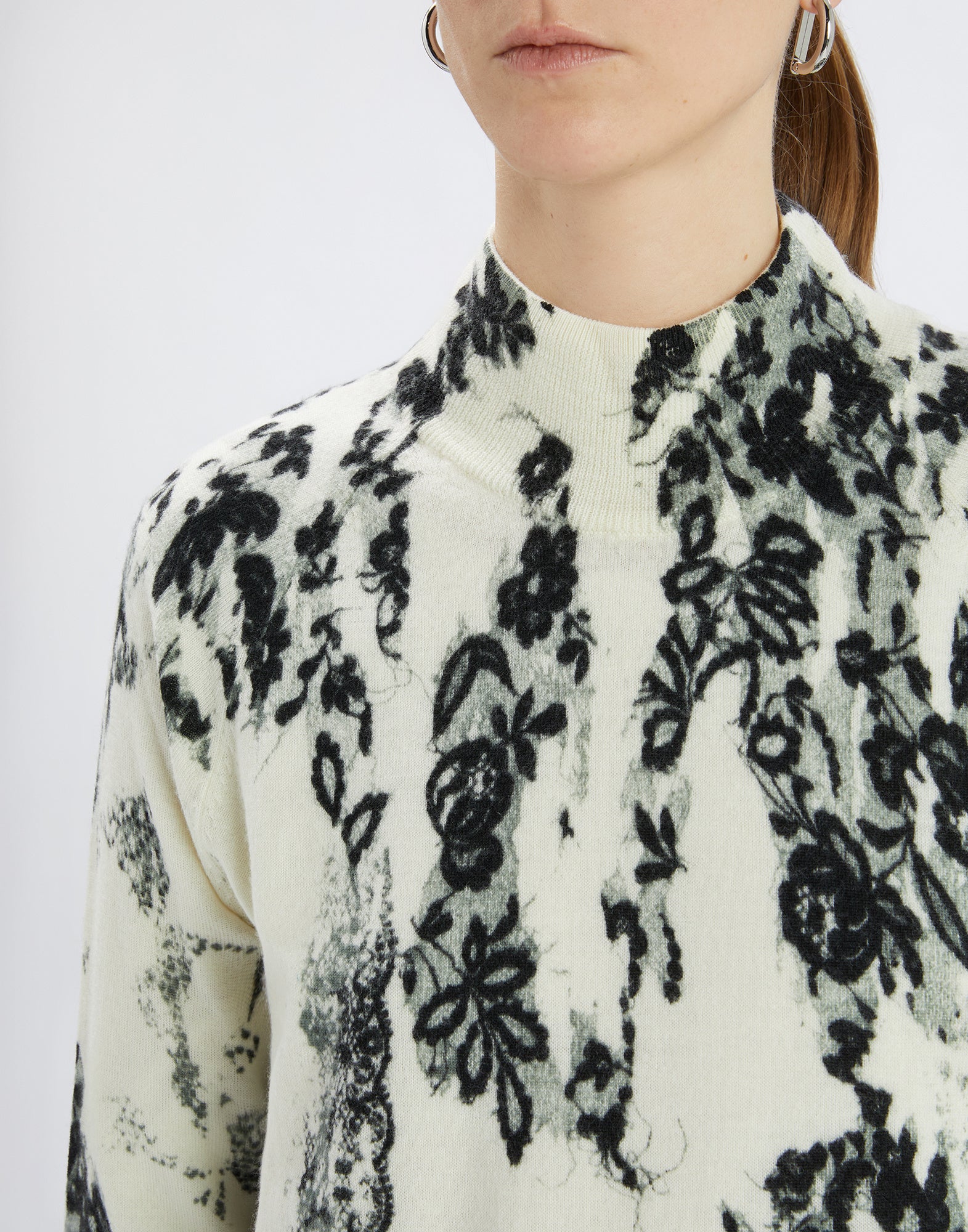 Detailansicht von vorne: RAMSEY Pullover mit Stehkragen, cremefarbener Grund und schwarzem floralem Muster, feine Merinowolle, weiche Textur.