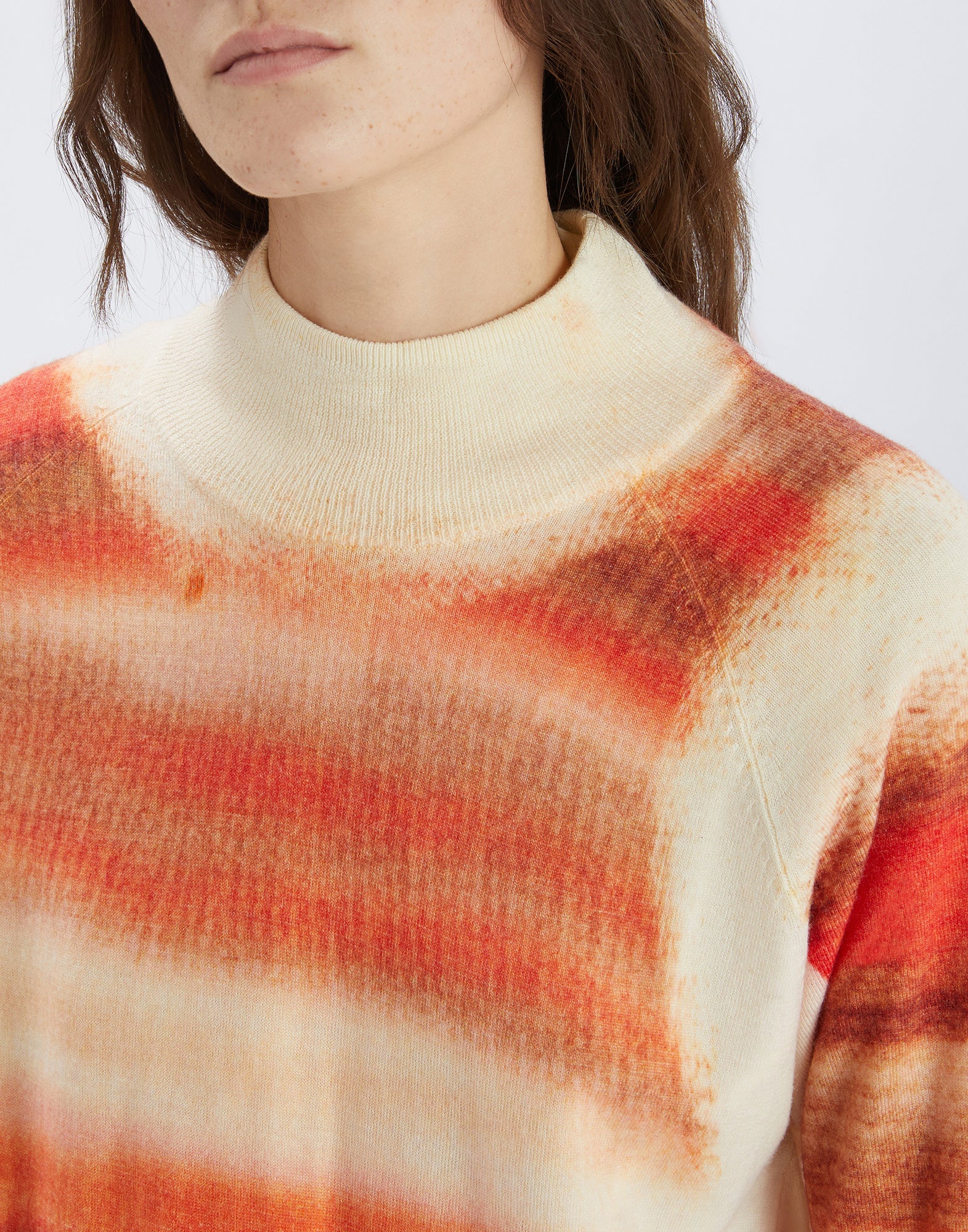 Front view of the RAMSEY merino wool sweater made of cream-colored fabric with artistic orange-toned stripe print and stand-up collar.