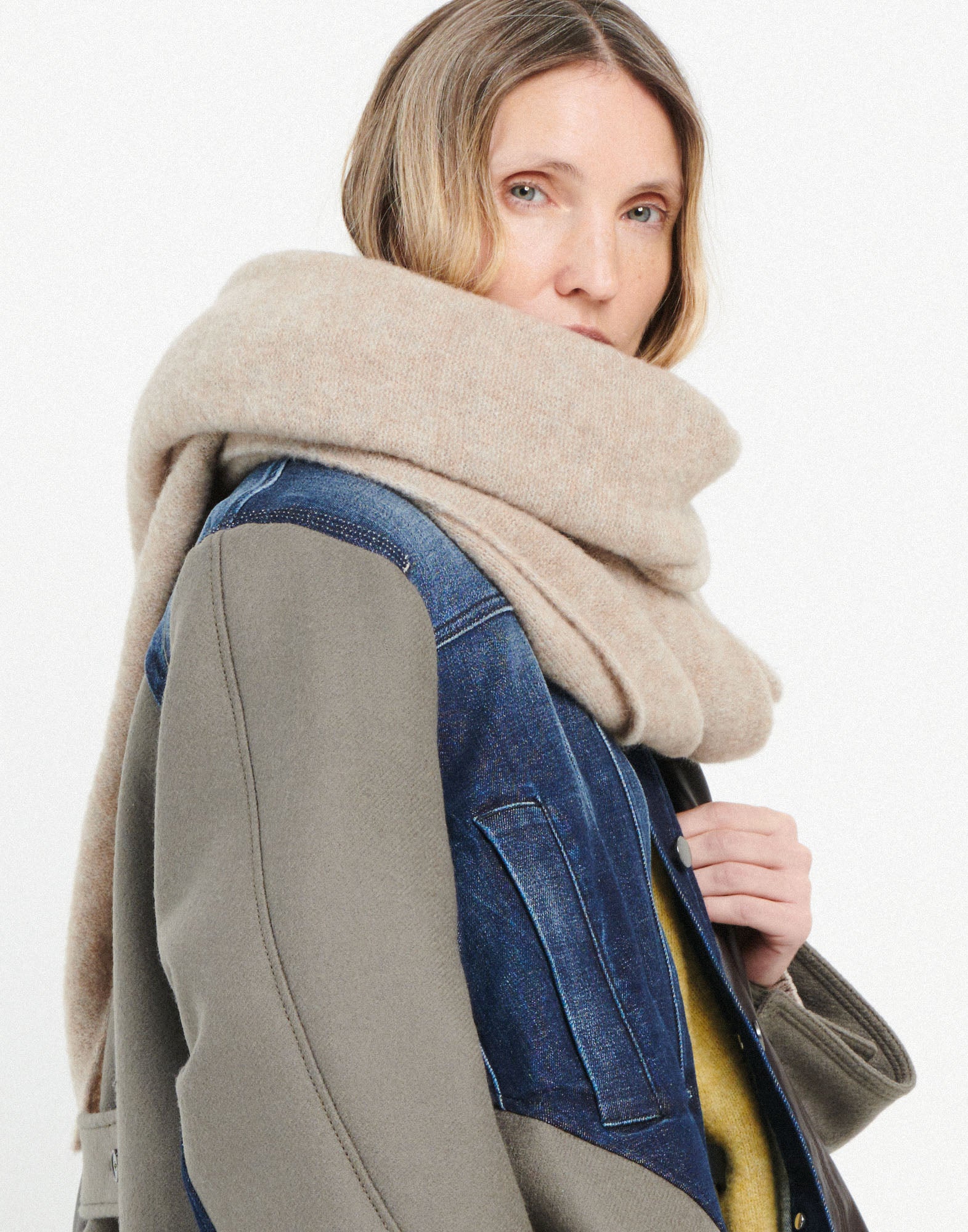 Frontalansicht: Eine Frau trägt den FROSTY Stretch-Alpakawollschal locker um den Hals. Der Schal ist voluminös, beige und sieht kuschelig aus.