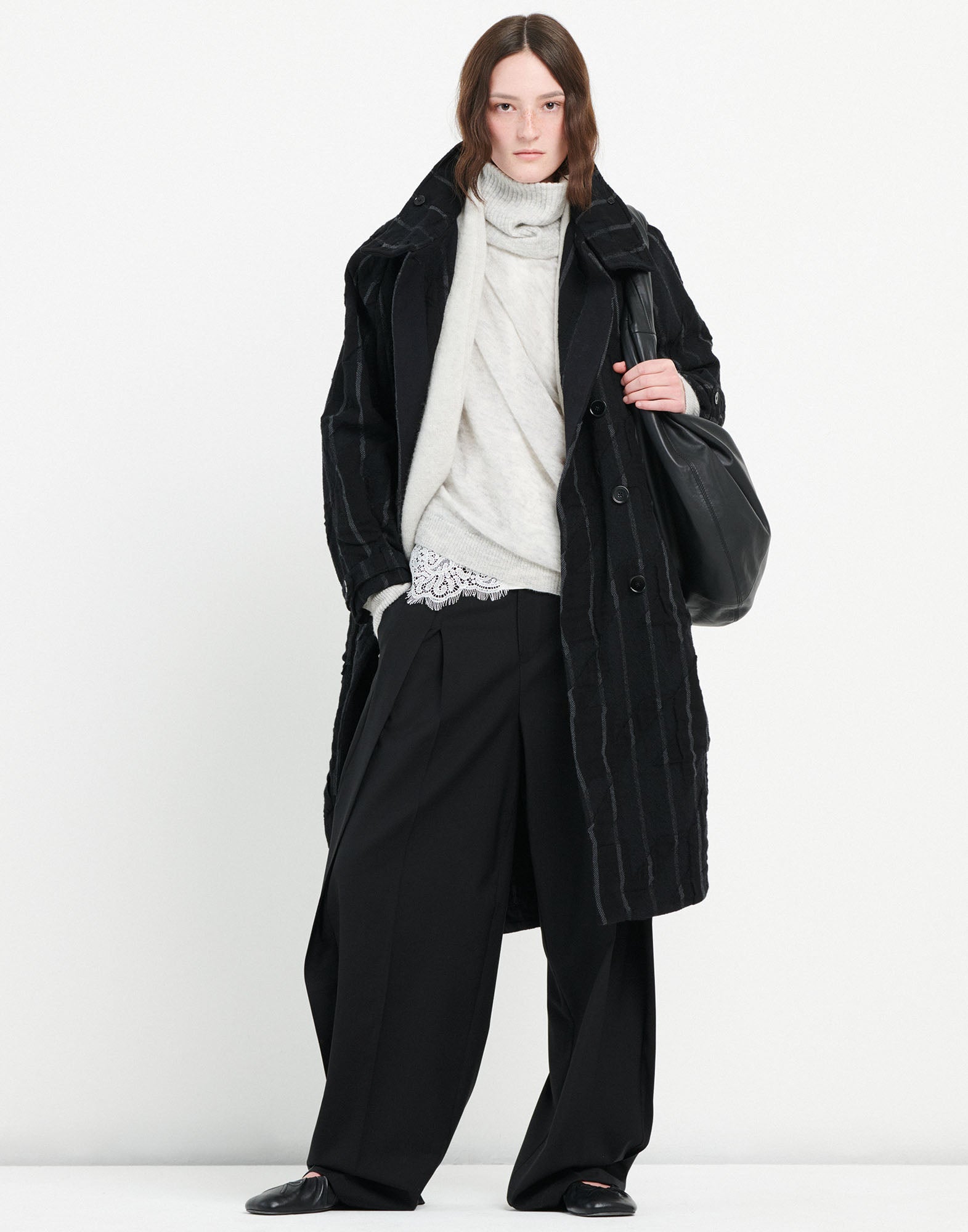 Front view: Person wears NEVERLAND pants made of extra-fine wool with double front pleats, wide leg, and modern waist belt buckle.