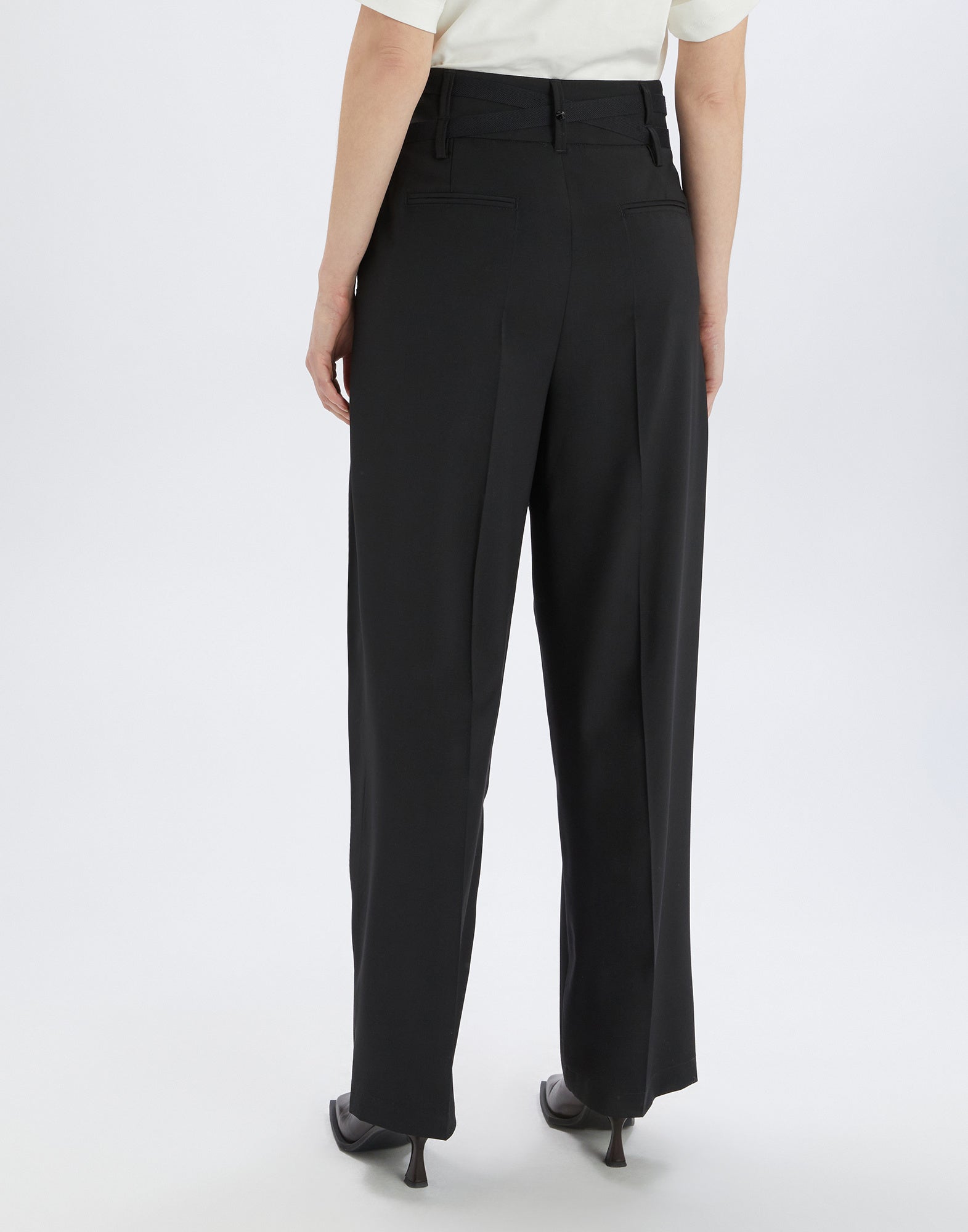 Back view of NEVERLAND pants in extra-fine black wool, featuring double waist belt, belt loops, welt pockets, and wide, fluid cut.