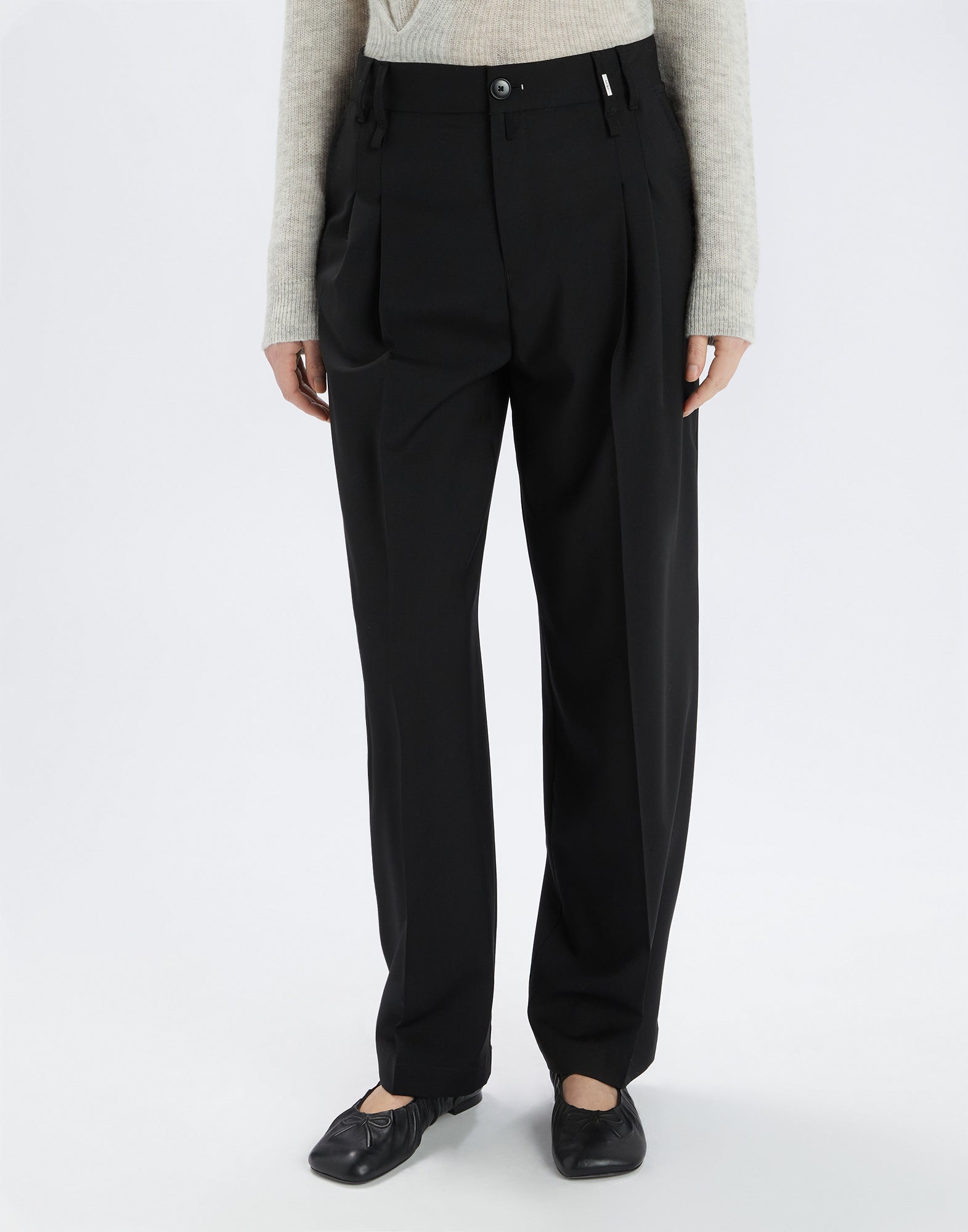 Front view of the black RELY pants in extra-fine wool, relaxed fit with front pleats and modern darted hem, worn by a person.