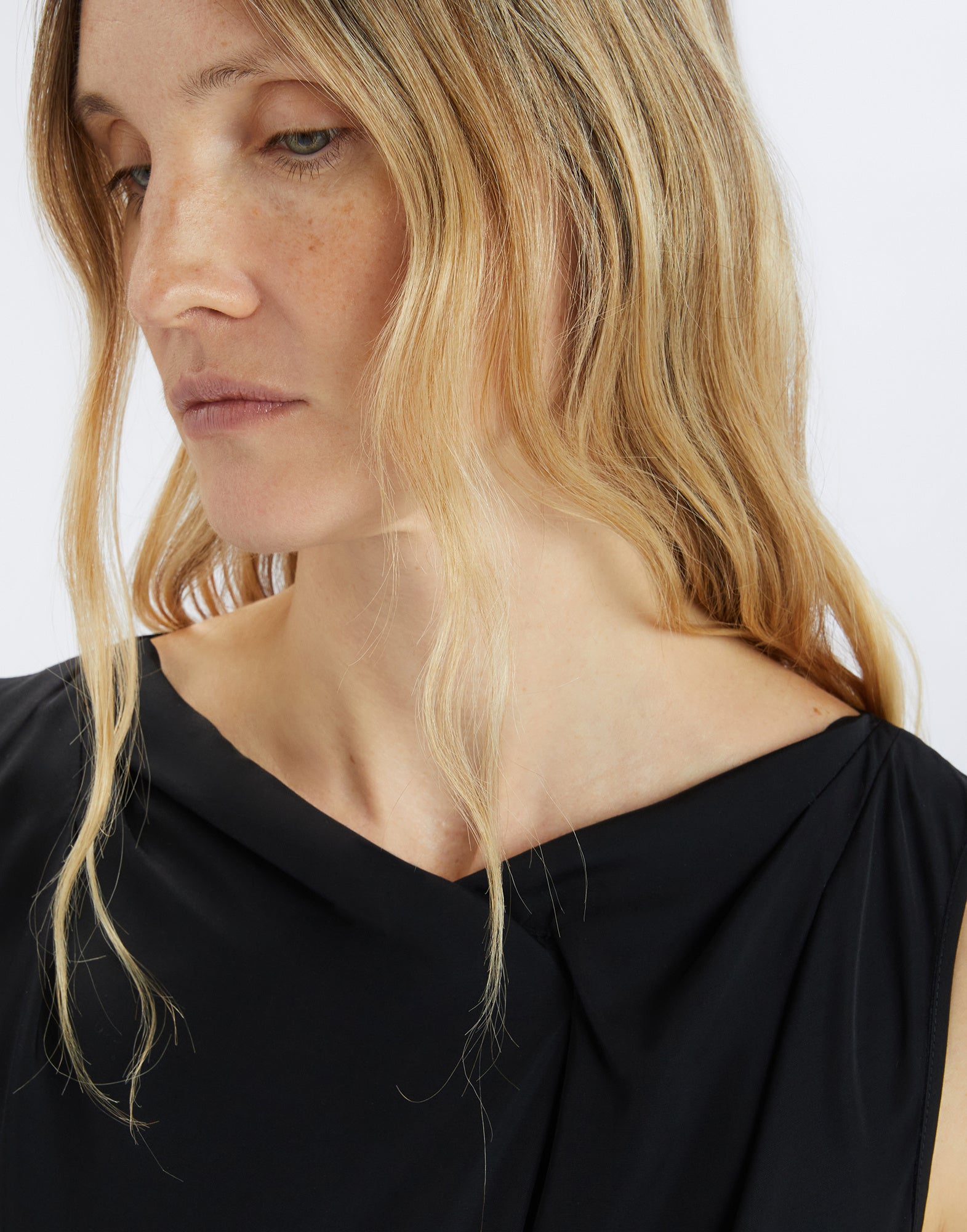 Detail view, frontal perspective: SOUND OFF dress with silky texture, lightweight fabric, asymmetric boat neckline, and refined side draping on the bodice.