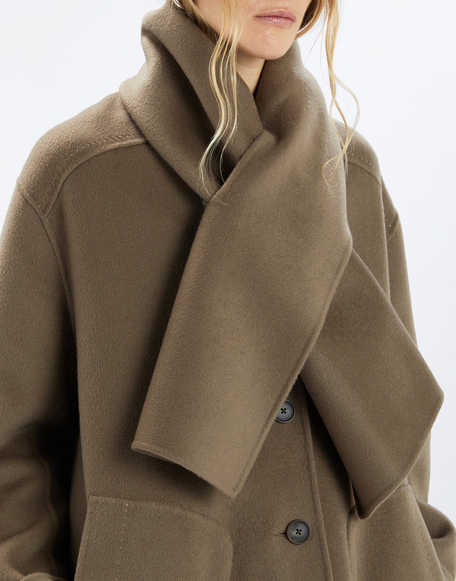 Detail view, front: SPIRE coat in soft brown double cashmere blend material, wide scarf, large welt pockets, and visible topstitching.