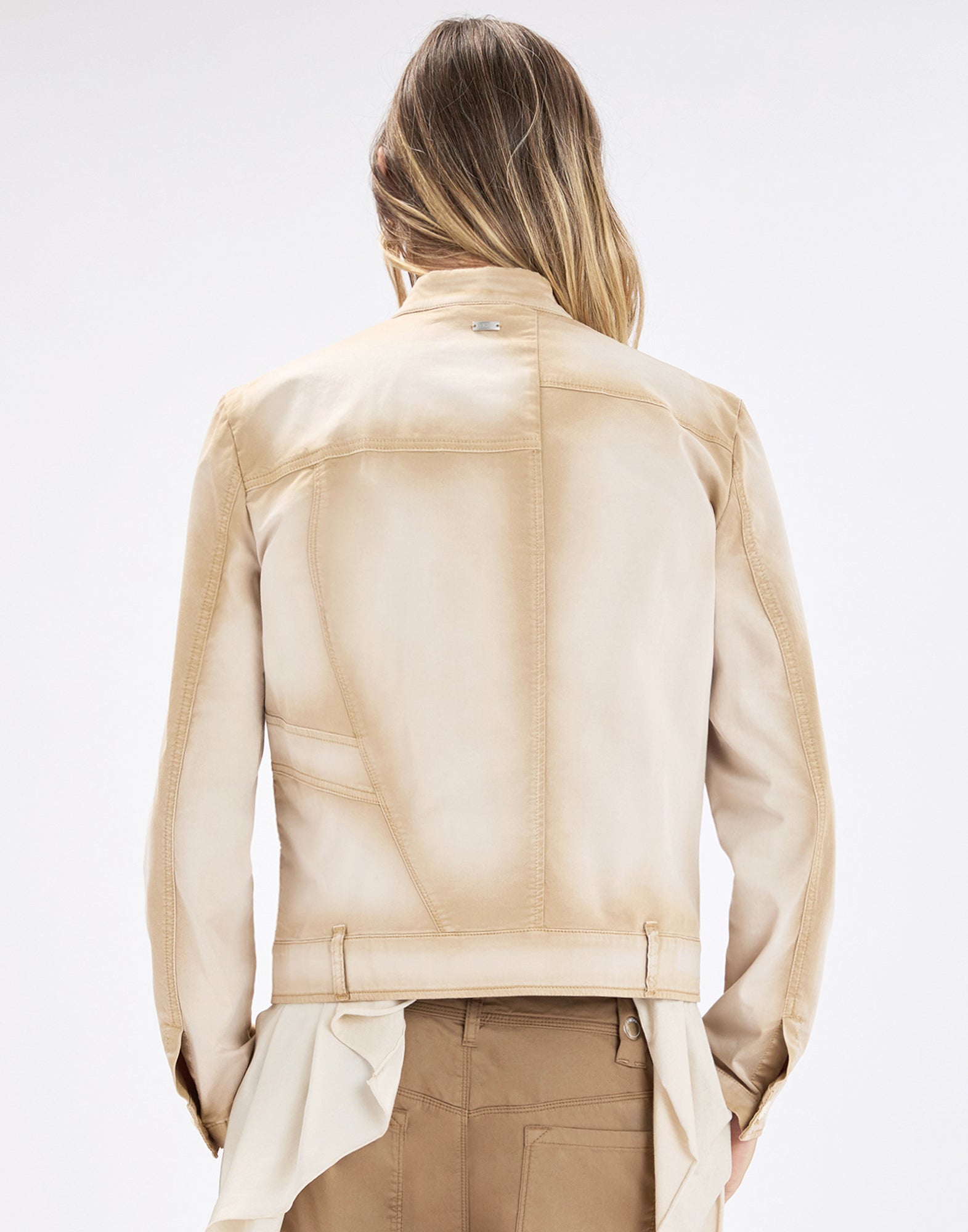 Rear view: person wearing the beige gradient ONSET cotton-satin jacket, unlined with visible seams and tabs at the hem, paired with brown trousers.