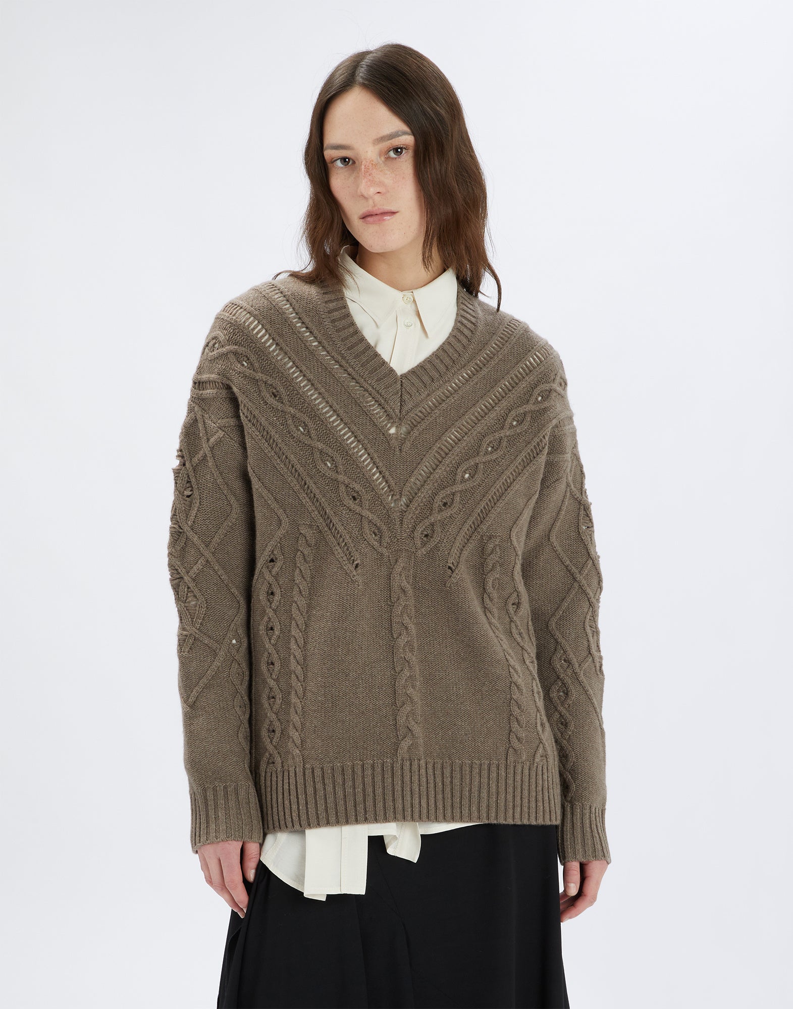 Front view of the NORTON sweater worn by a model. The sweater shows wide ribs, diagonal openwork patterns, and sinuous cable knits in taupe.