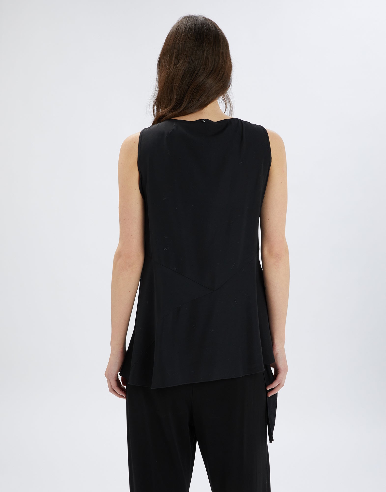 Rear view of the sleeveless TIMBRELL top in black with straight cut, asymmetric hem, and lightweight fabric, worn by a woman.