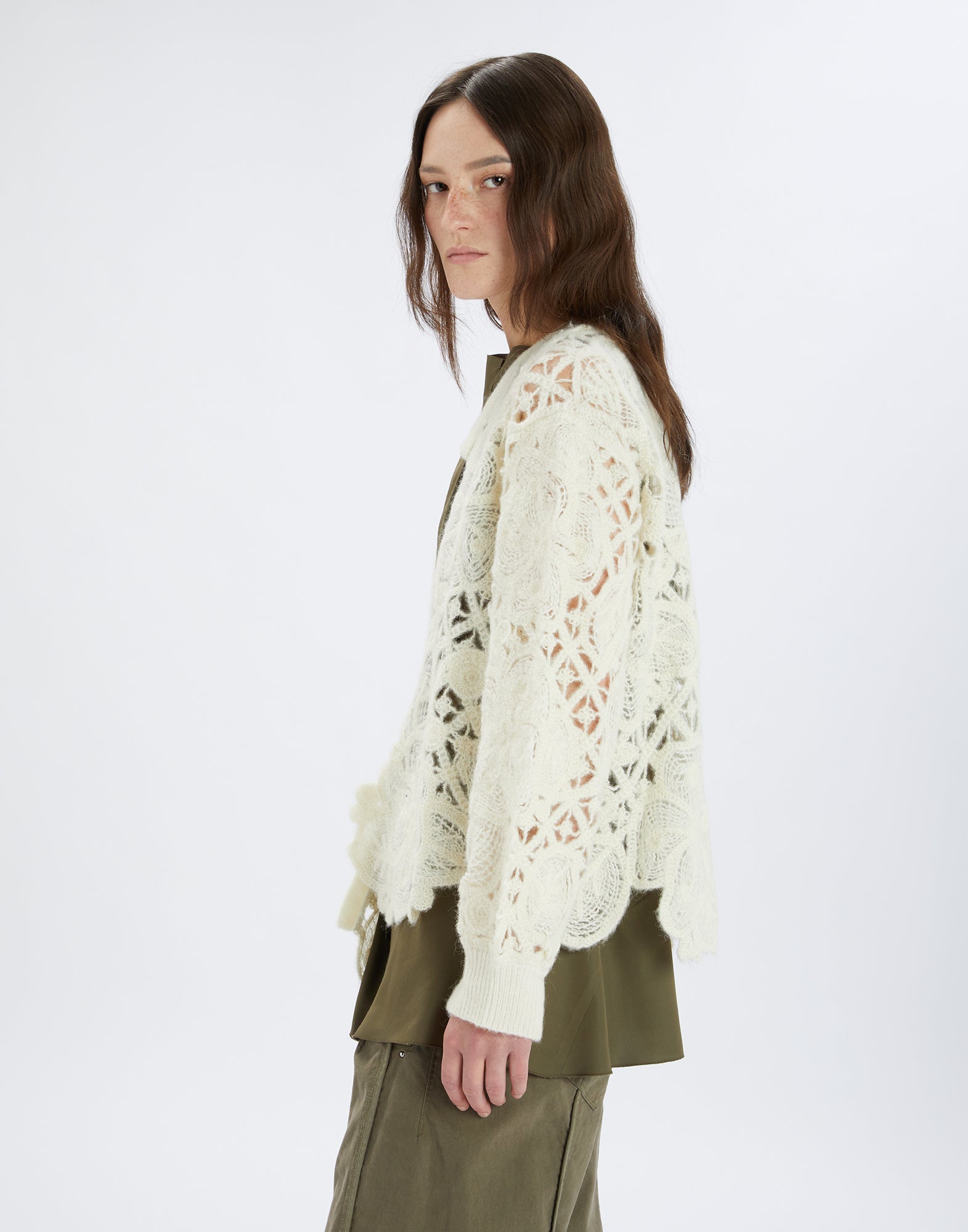 Side view of a model wearing the BOHEME cardigan with floral openwork embroidery and asymmetric hem. The cardigan looks soft and feminine.