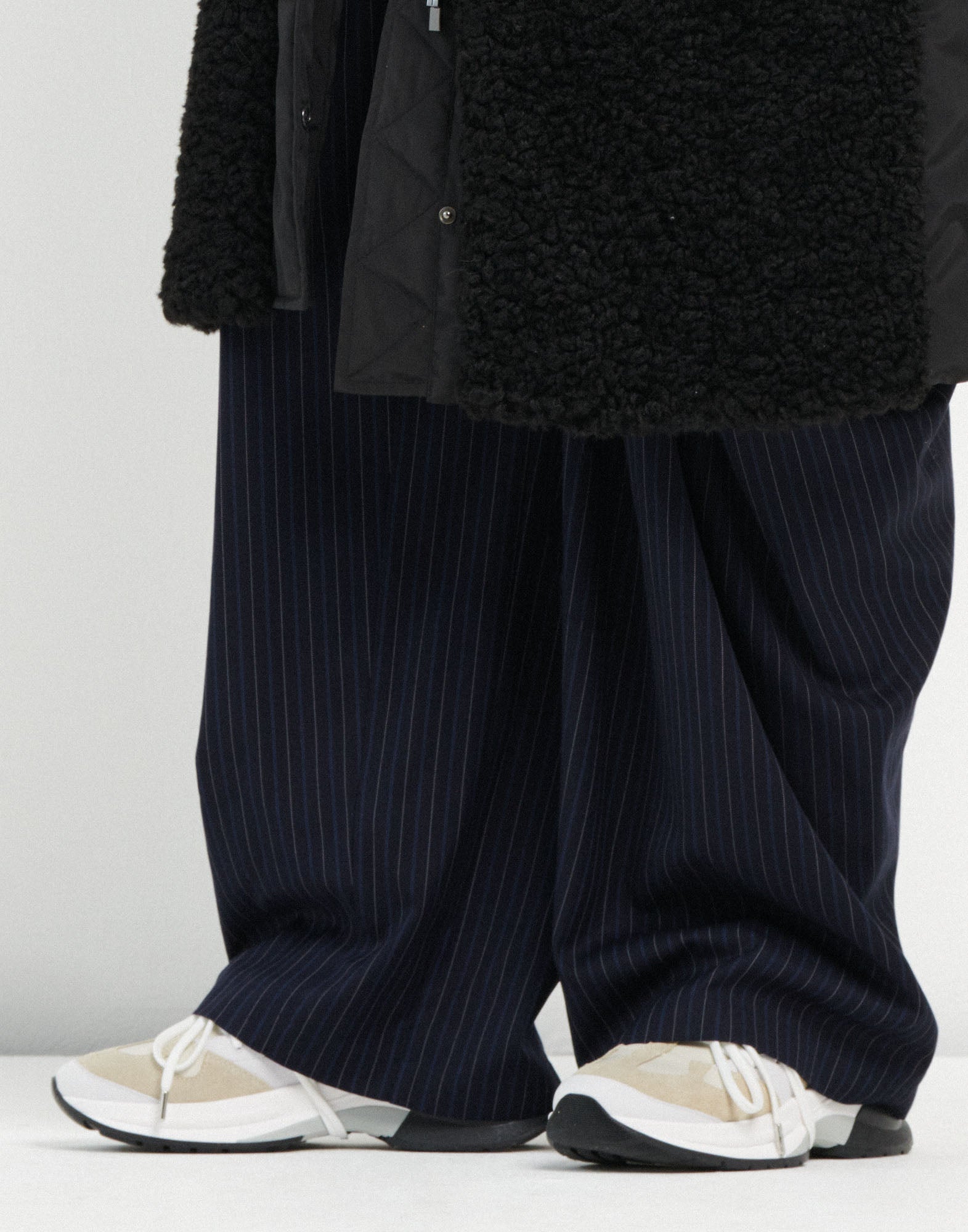 Front view of the PARTIAL sneaker worn with wide, dark blue striped pants. The shoes feature various light, tonal leathers, white laces, and a striking color-block sole.