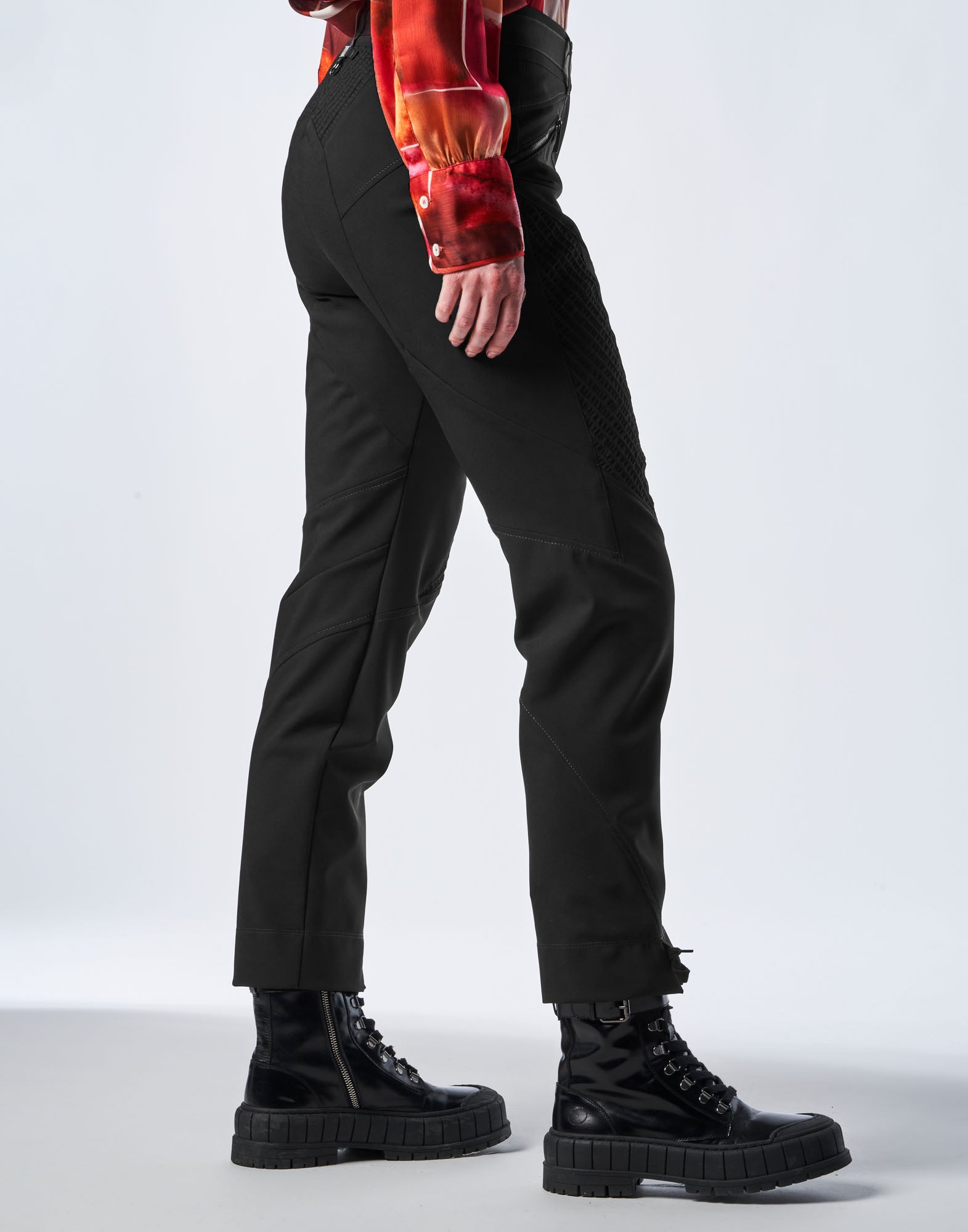 Seitenansicht einer Person, die die schwarze Funktions-Twill-Hose DEVIATE trägt, mit sichtbaren Kontrastnähten und Motorrad-inspirierten, diagonalen Details am Bein.