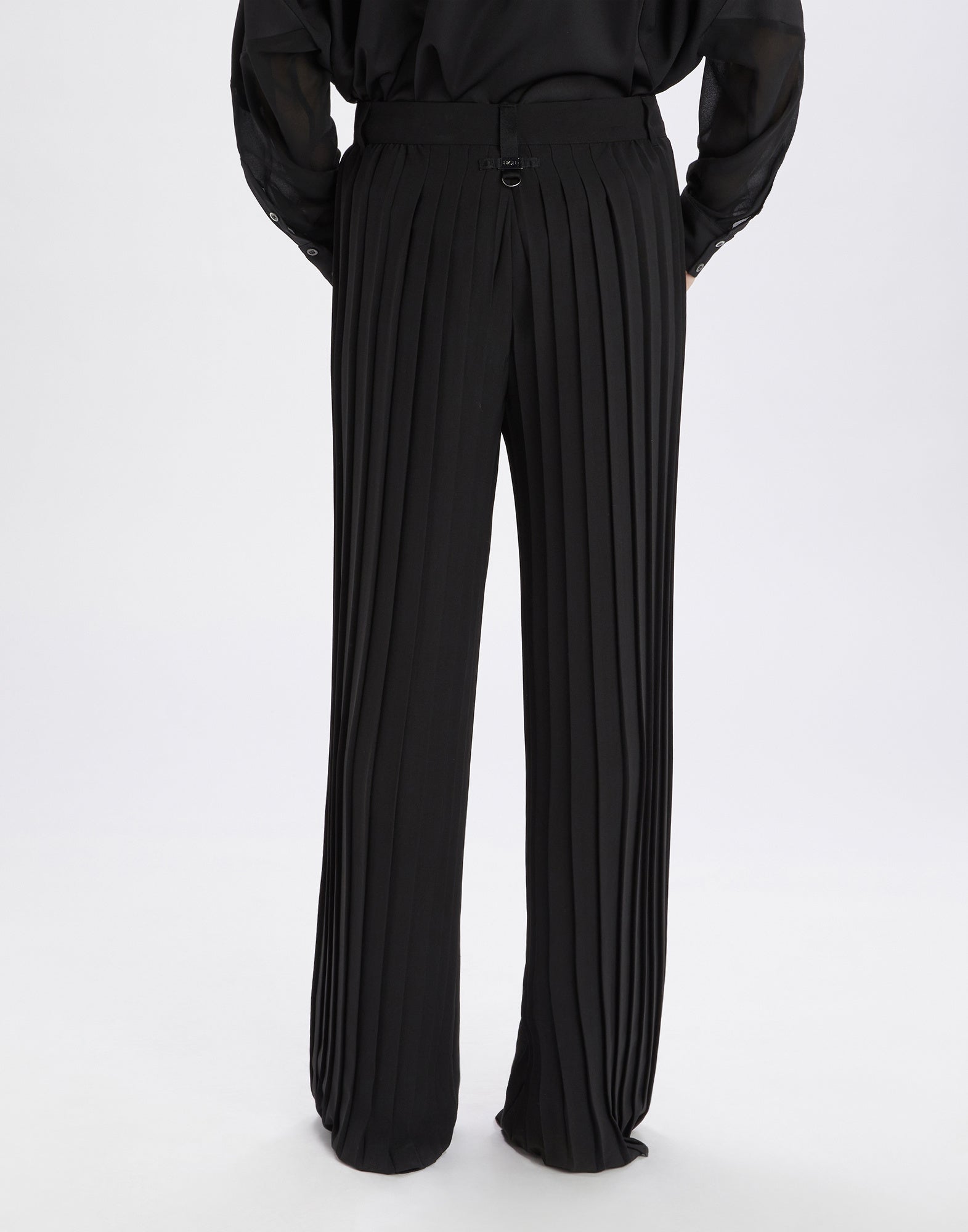 Rear view: DREW palazzo trousers in lightweight worsted wool with striking vertical pleats, straight leg, and waistband with belt loops, worn by a person.