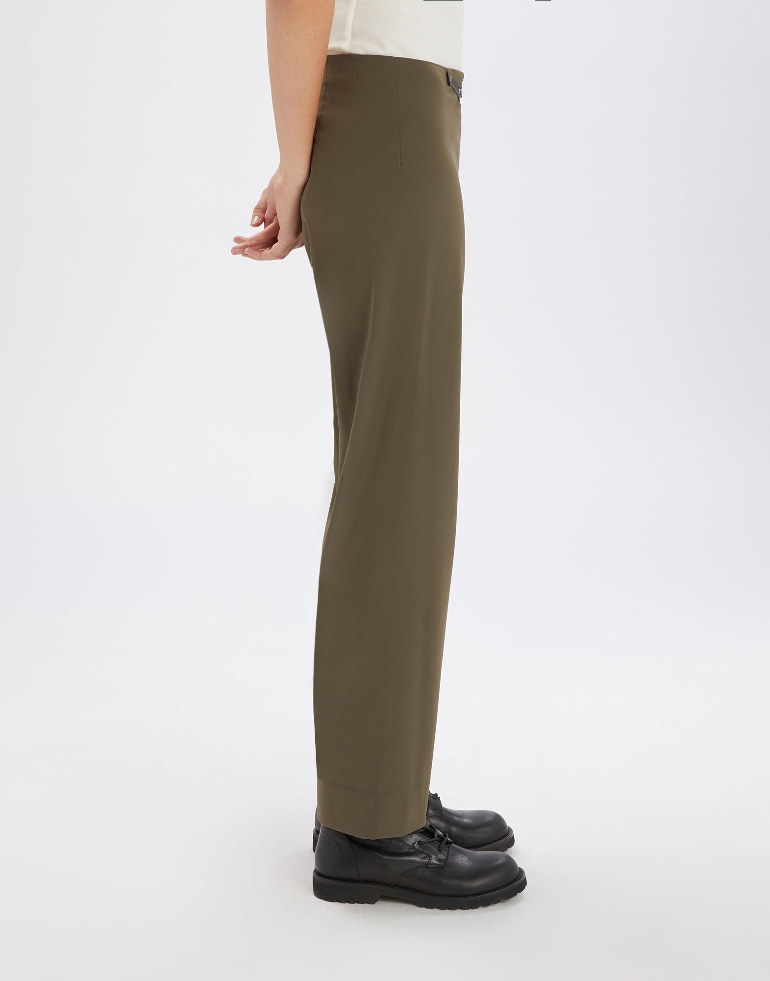 Side view of PROCEED pants in olive green. Pants without visible seams or pockets, featuring high hem, elastic waistband, and belt loops at the back.