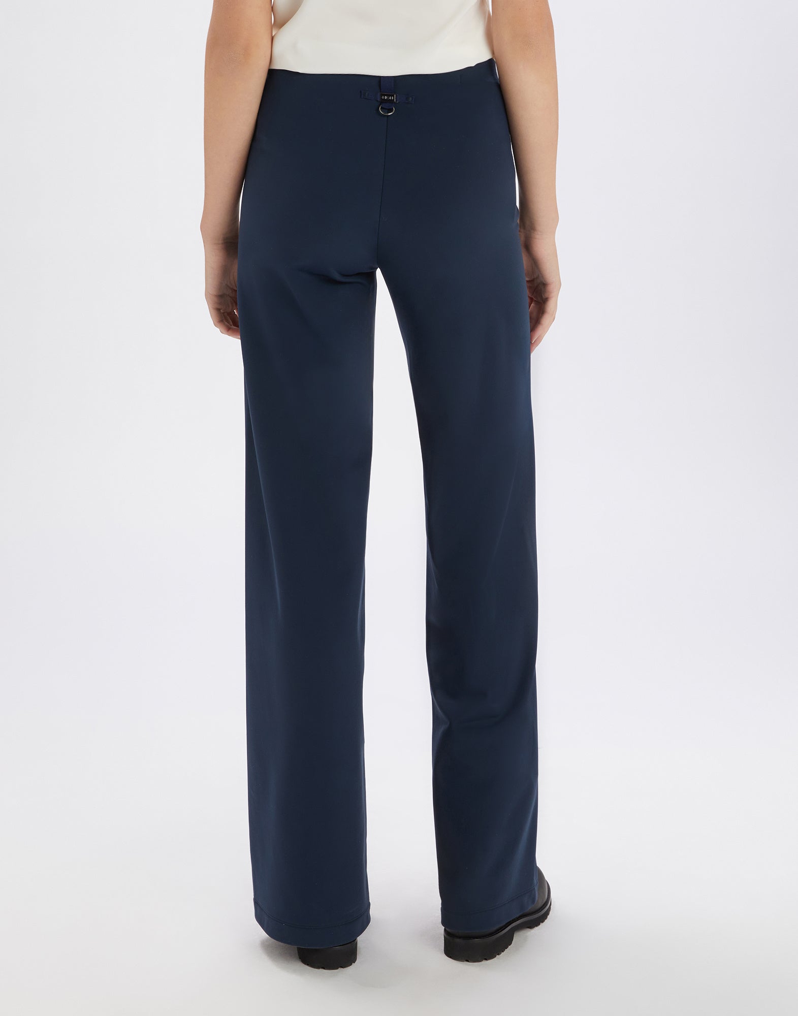 Rückansicht einer Person, die die Hose MARCH in Dunkelblau trägt. Die Hose hat einen elastischen Bund, gerade geschnittene Beine und minimalistische Details.