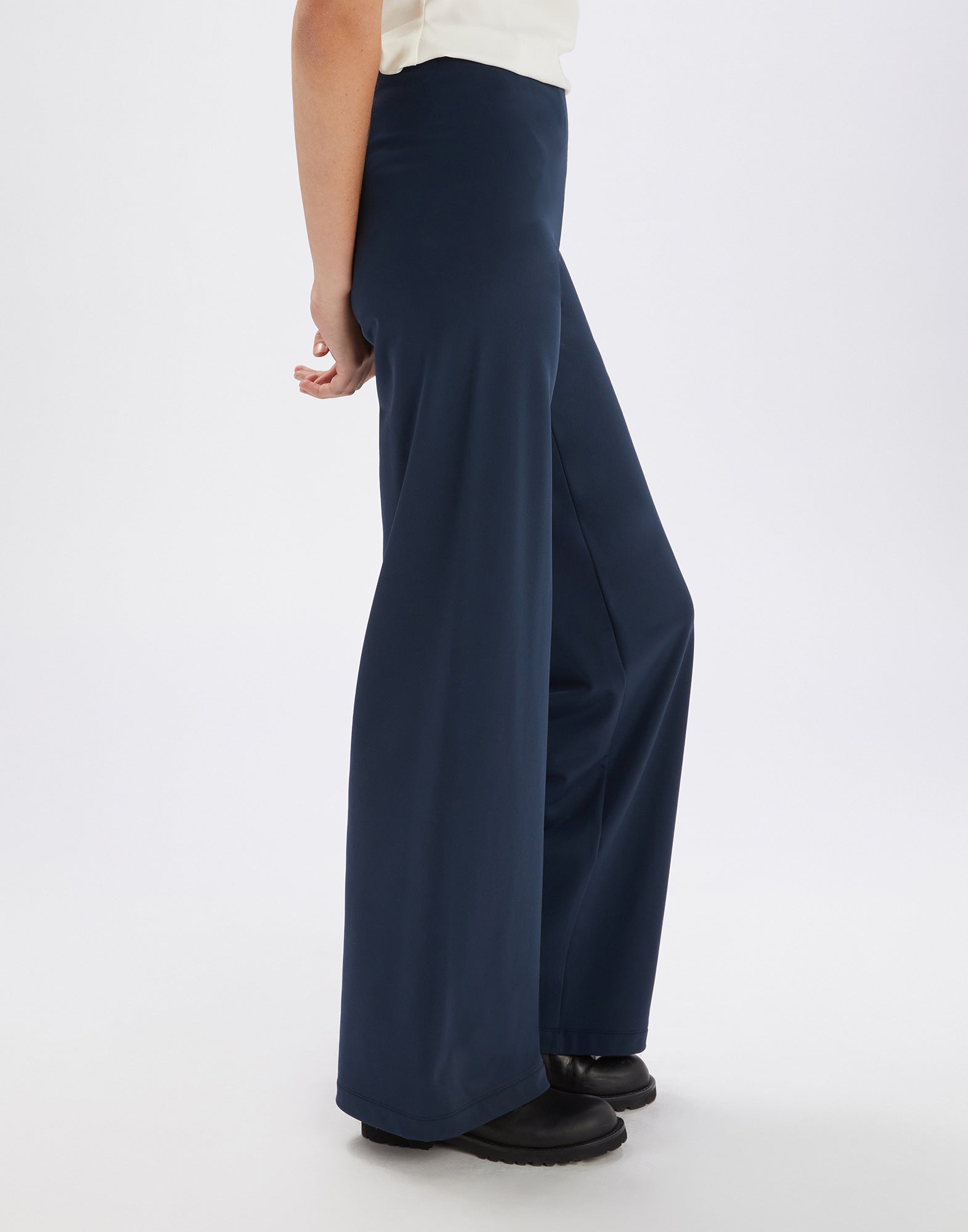 Seitenansicht der Hose MARCH in dunklem Blau, weit geschnitten, mit elastischem Bund, leicht fallend, ohne sichtbare Taschen, getragen mit schwarzen Schuhen.