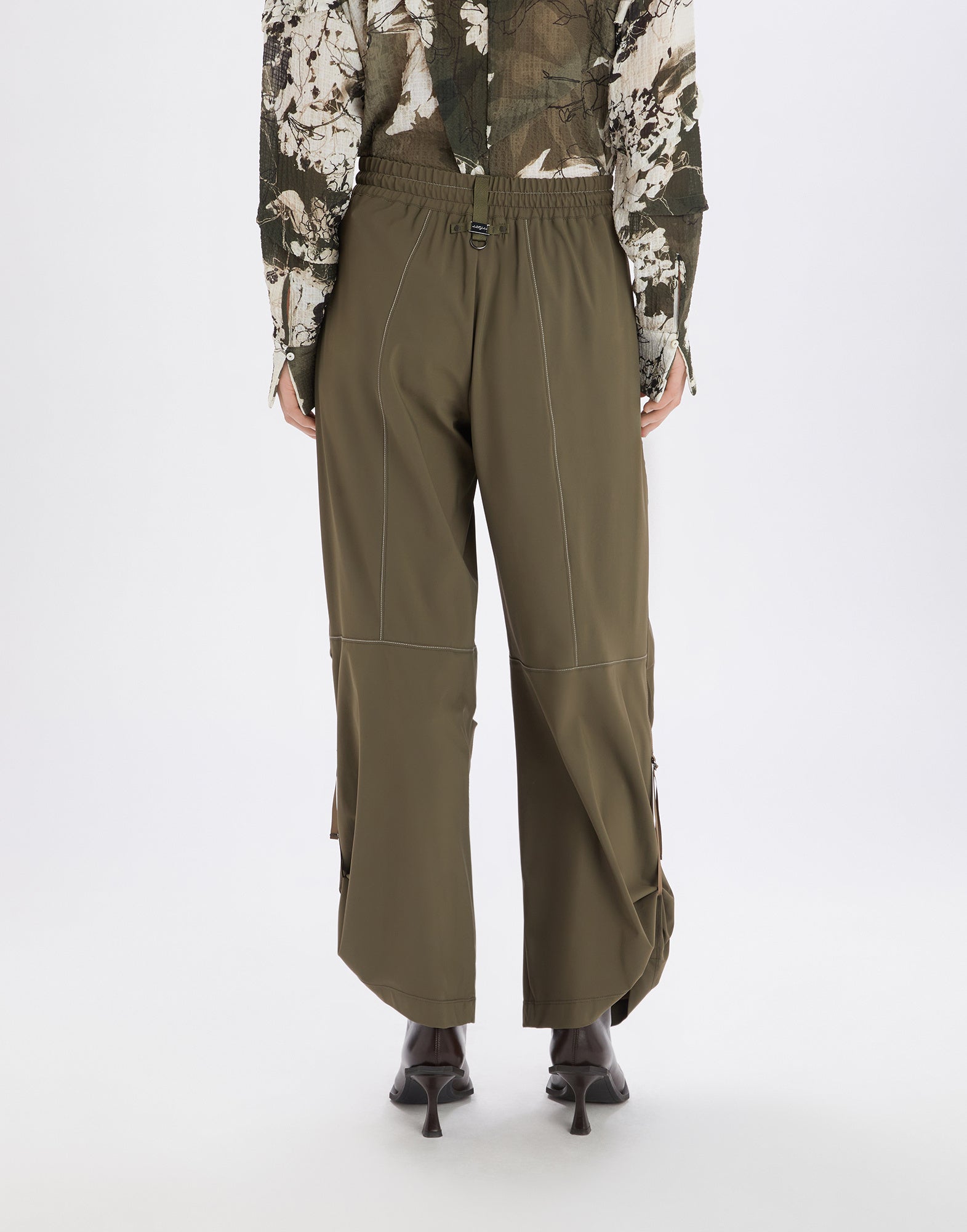 Rückansicht der OUTGOING Hose in Olivgrün, locker geschnitten mit elastischem Bund, kleiner D-Ring und sichtbaren Steppnähten sowie ausgestellten Beinen.
