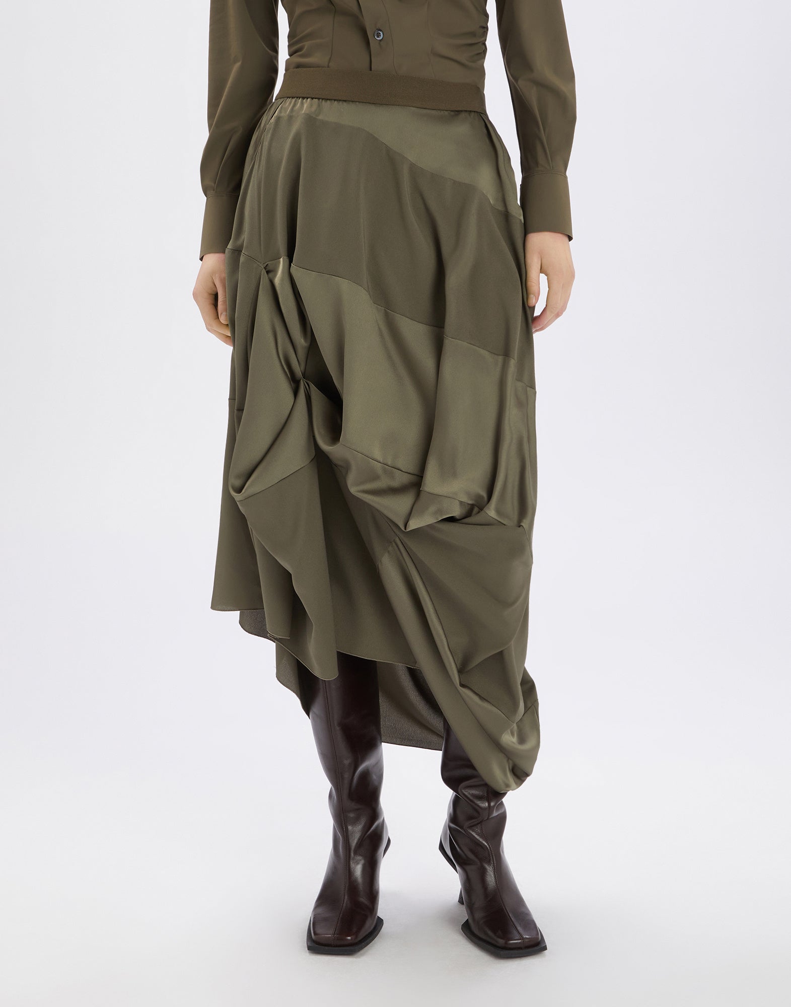 Frontalansicht des Rocks GEEK in olivgrün aus fließendem Tech-Satin, mit asymmetrischem, drapiertem Schnitt, elastischem Bund, midi-langer Länge und ohne Futter.