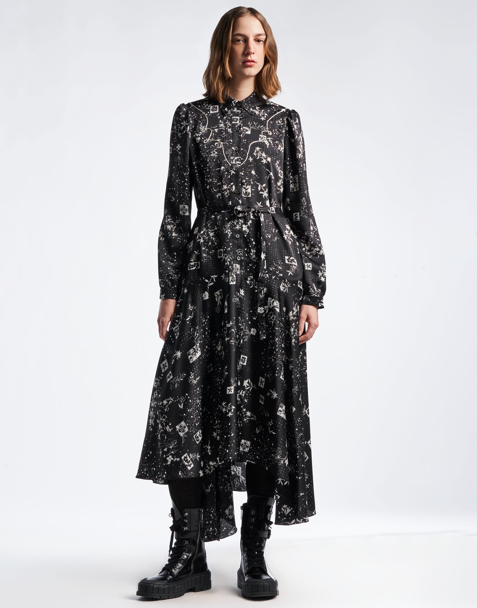 Frontalansicht: COMPELLING Hemdkleid aus schwarzem Funktionssatin mit geometrischem Blumenmuster, elfenbeinfarbenen Farbflecken, Klappkragen, langen Ärmeln und weitem, asymmetrischem Rock.