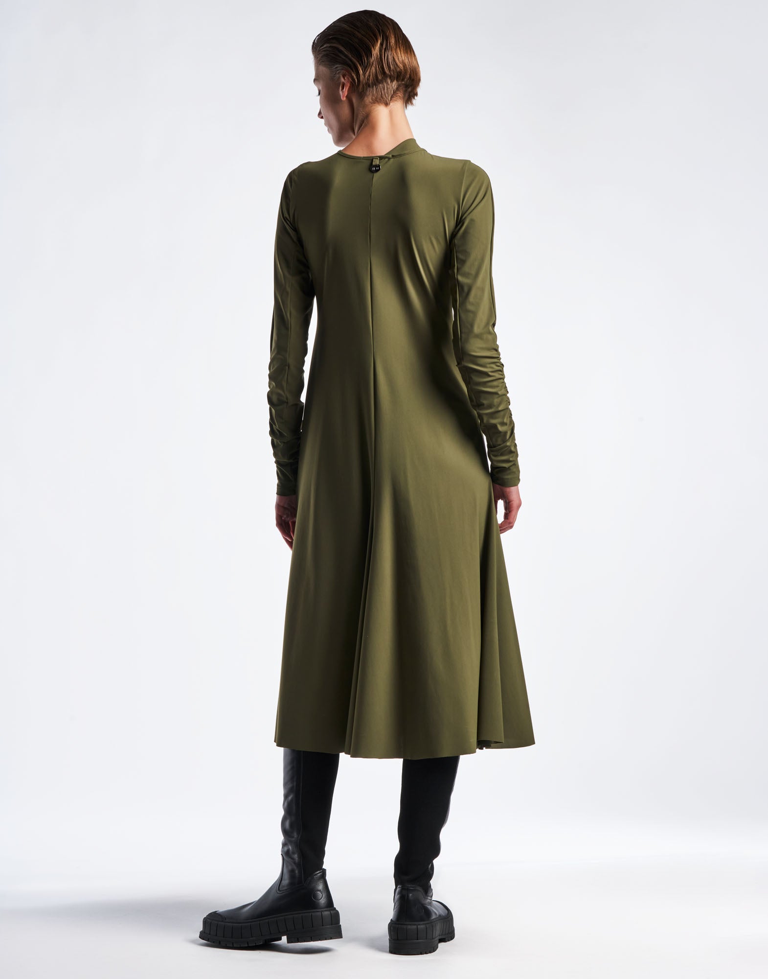 Rear view of SINCERELY Kleid in olivgrünem Sensitive(R) Sportjersey, mit ausgestelltem Rock, langen, ruhierten Ärmeln und rundem Halsausschnitt, knielang getragen.