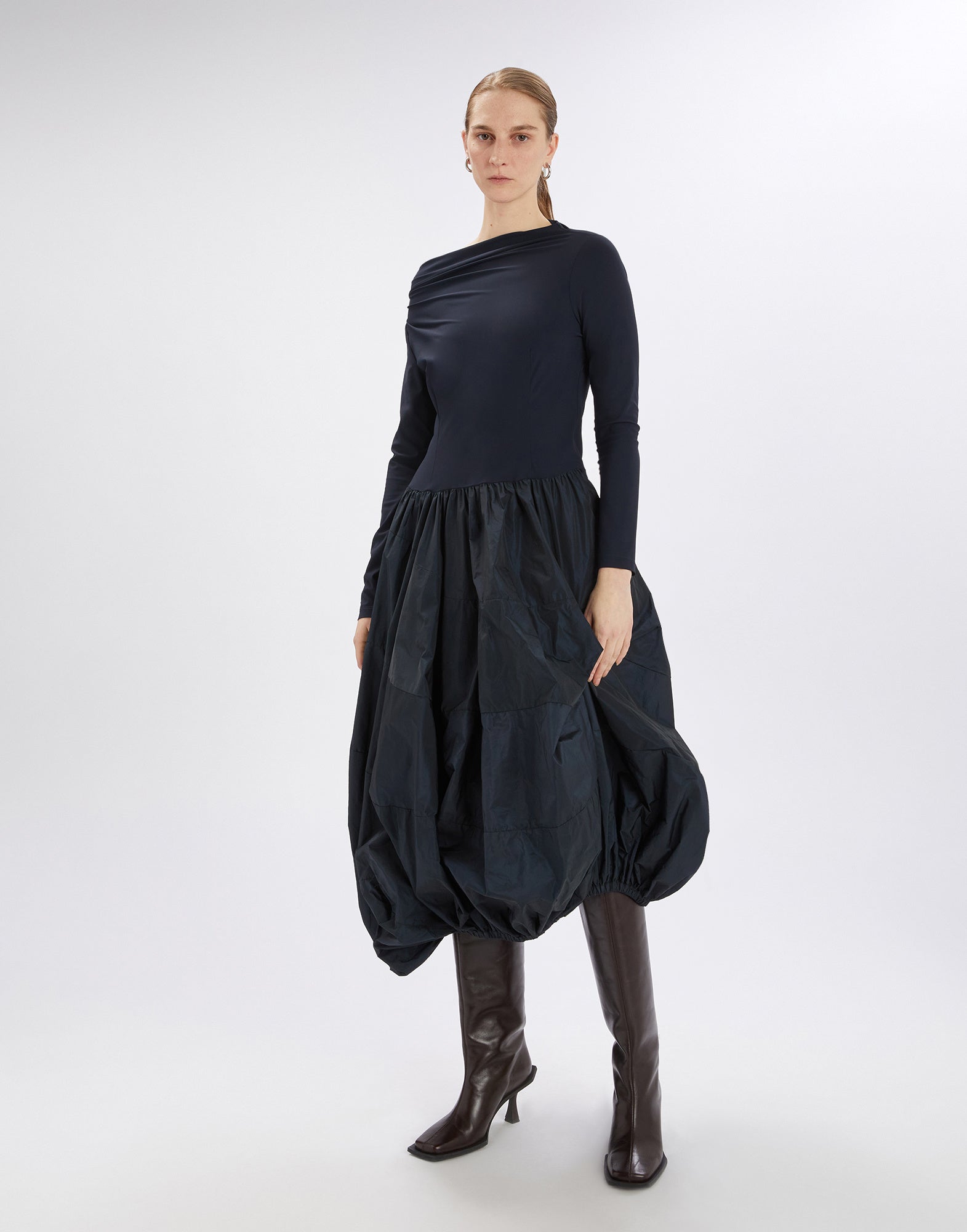 Frontalansicht des Kleids GRID mit asymmetrischem Boot-Ausschnitt, langen Ärmeln, figurbetontem Oberteil aus Sensitive(R) und ballonförmigem Rock aus glänzendem Taft.