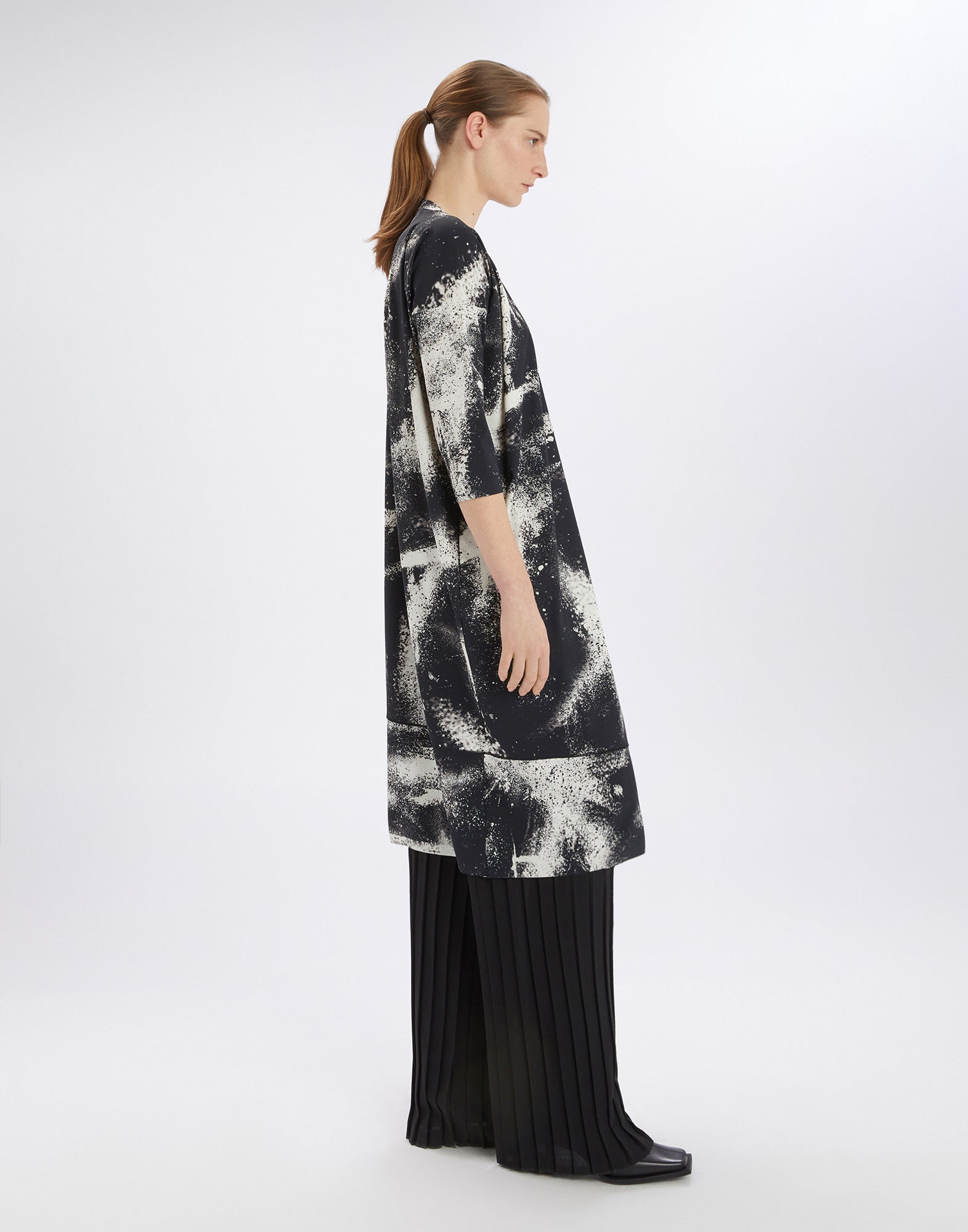 Side view of the PRELUDE dress with black-and-white spray-effect print, flowing asymmetric fit, and three-quarter sleeves on a model.