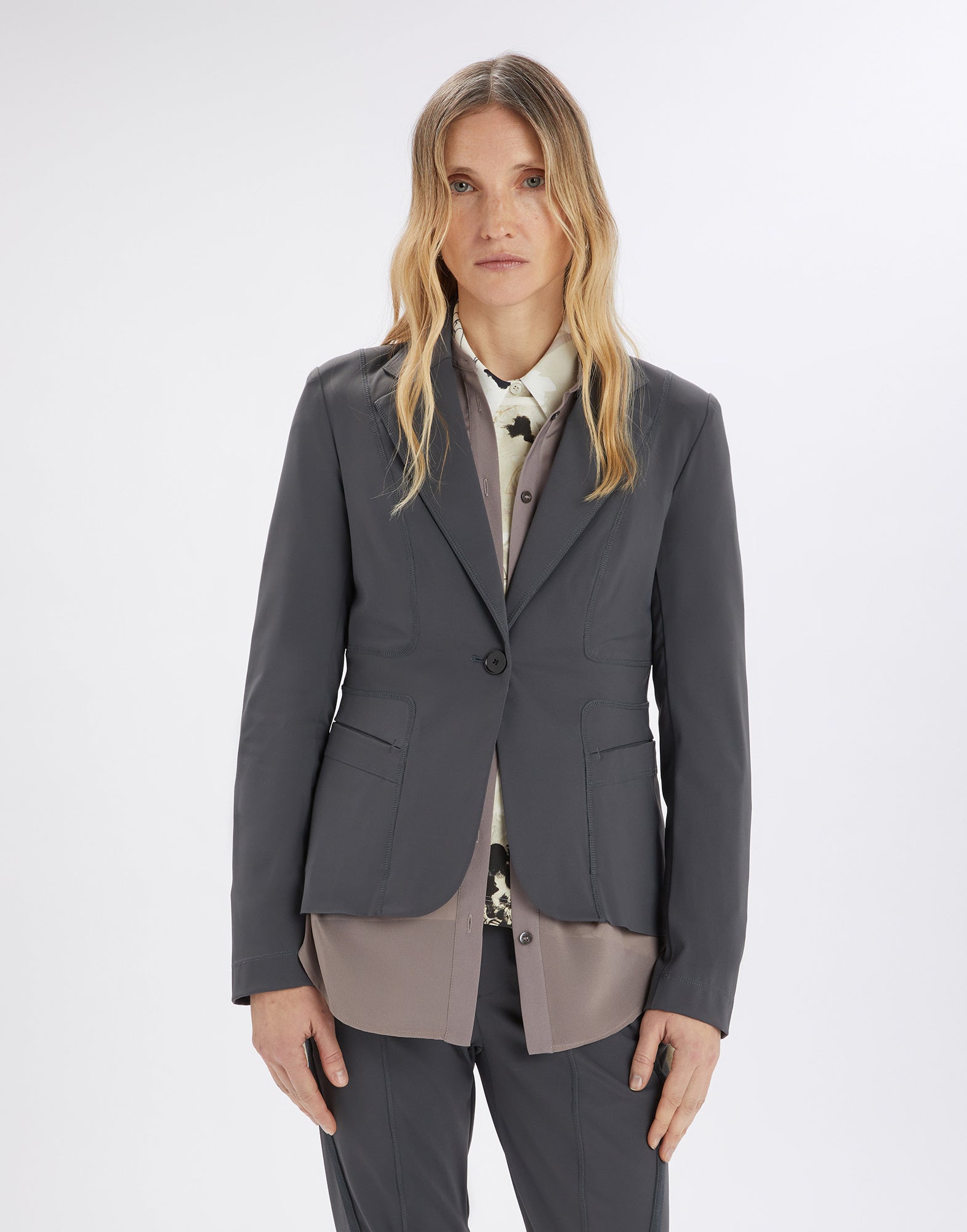 Front view of a woman wearing the tailored NO-WAY blazer in dark grey scuba fabric with shoulder pads, visible seams, and side pockets.
