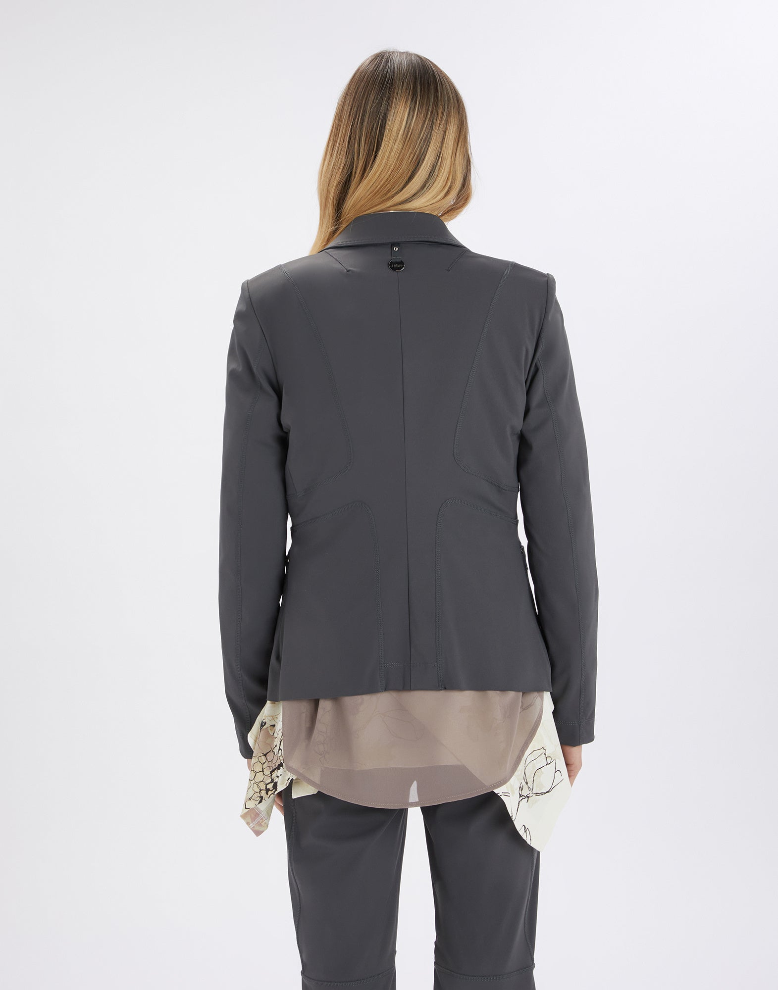 Back view of a person wearing the NO-WAY blazer made from compact, dark grey scuba fabric. Exposed seams accentuate the structured, tailored fit.