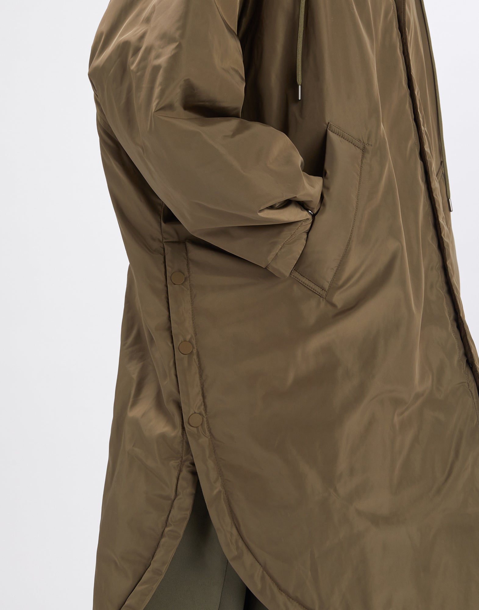 Detailansicht zeigt seitliche Knöpfe, Kimono-Ärmel und Seitentasche des olivgrünen Parka COFFER mit glattem, leicht gepolstertem Material in technisch-satiniertem Look.