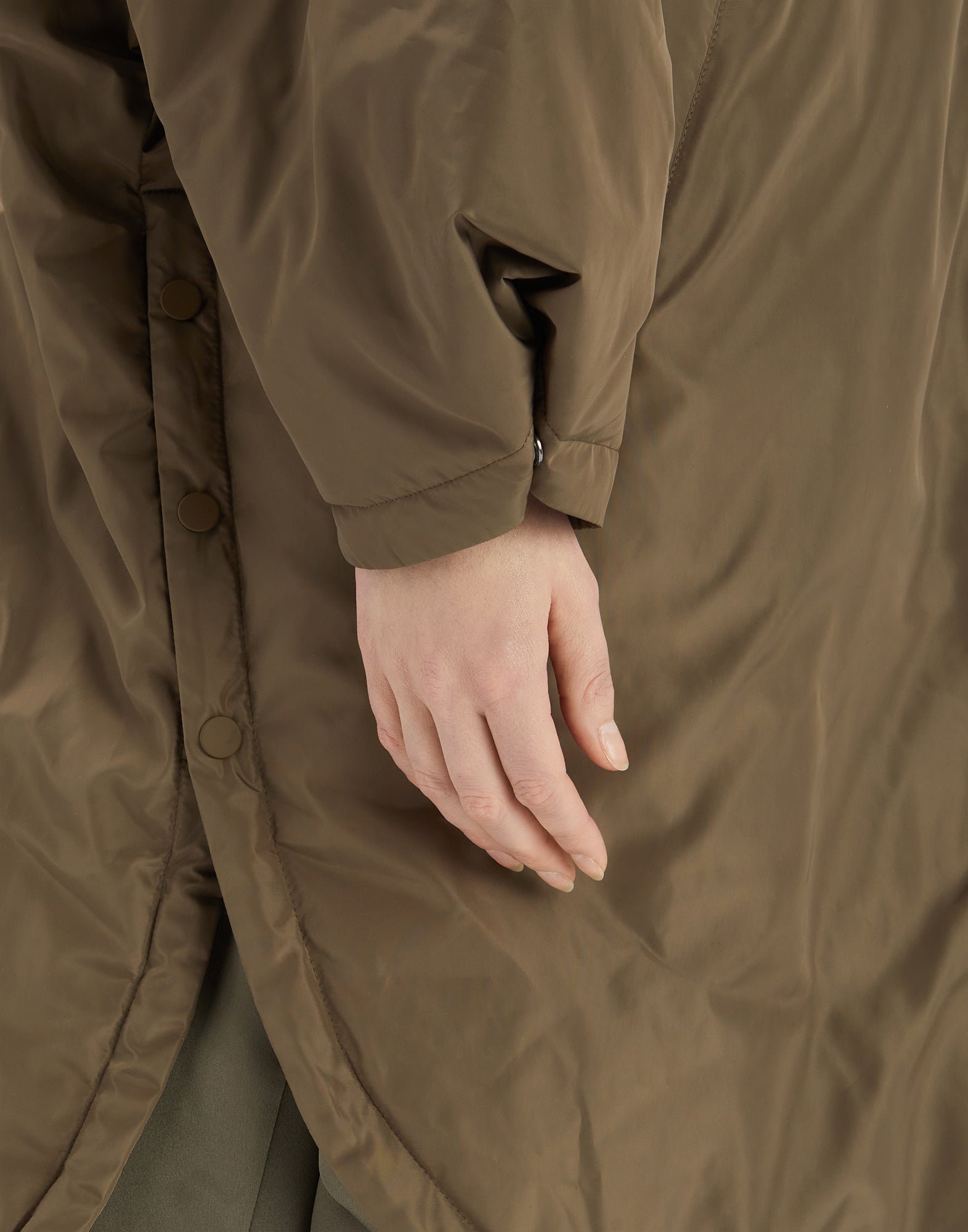 Detailansicht des COFFER Parkas zeigt eine Hand, die an der seitlichen Knopfleiste und dem abgerundeten, wasserabweisenden Stoffsaum entlanggelegt ist.