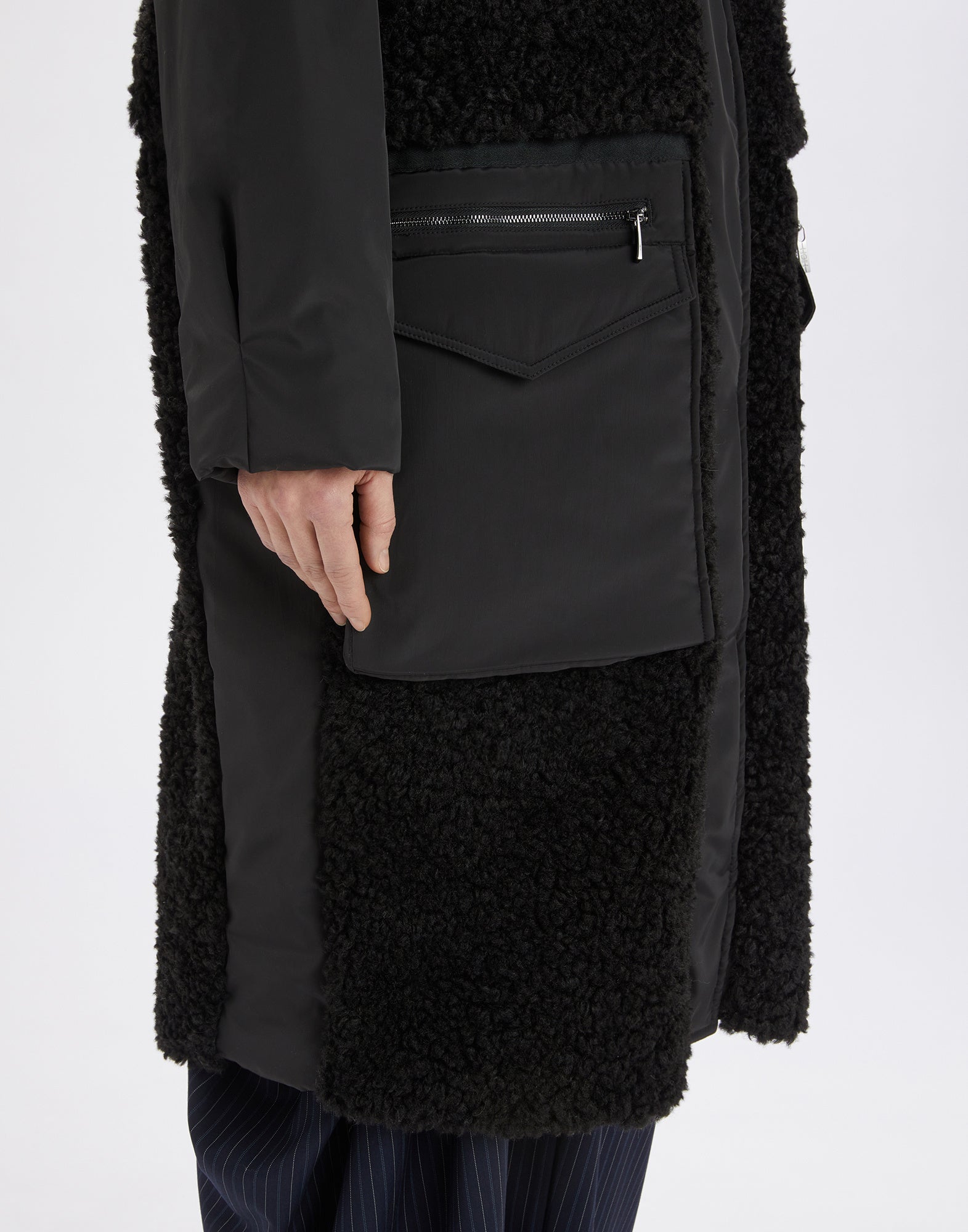 Detailansicht der ANNOTATE Mantel-Tasche mit Sherpa-Gewebe, sichtbarem Reißverschluss und Nylon-Einsatz aus seitlicher Perspektive am Oberschenkel.