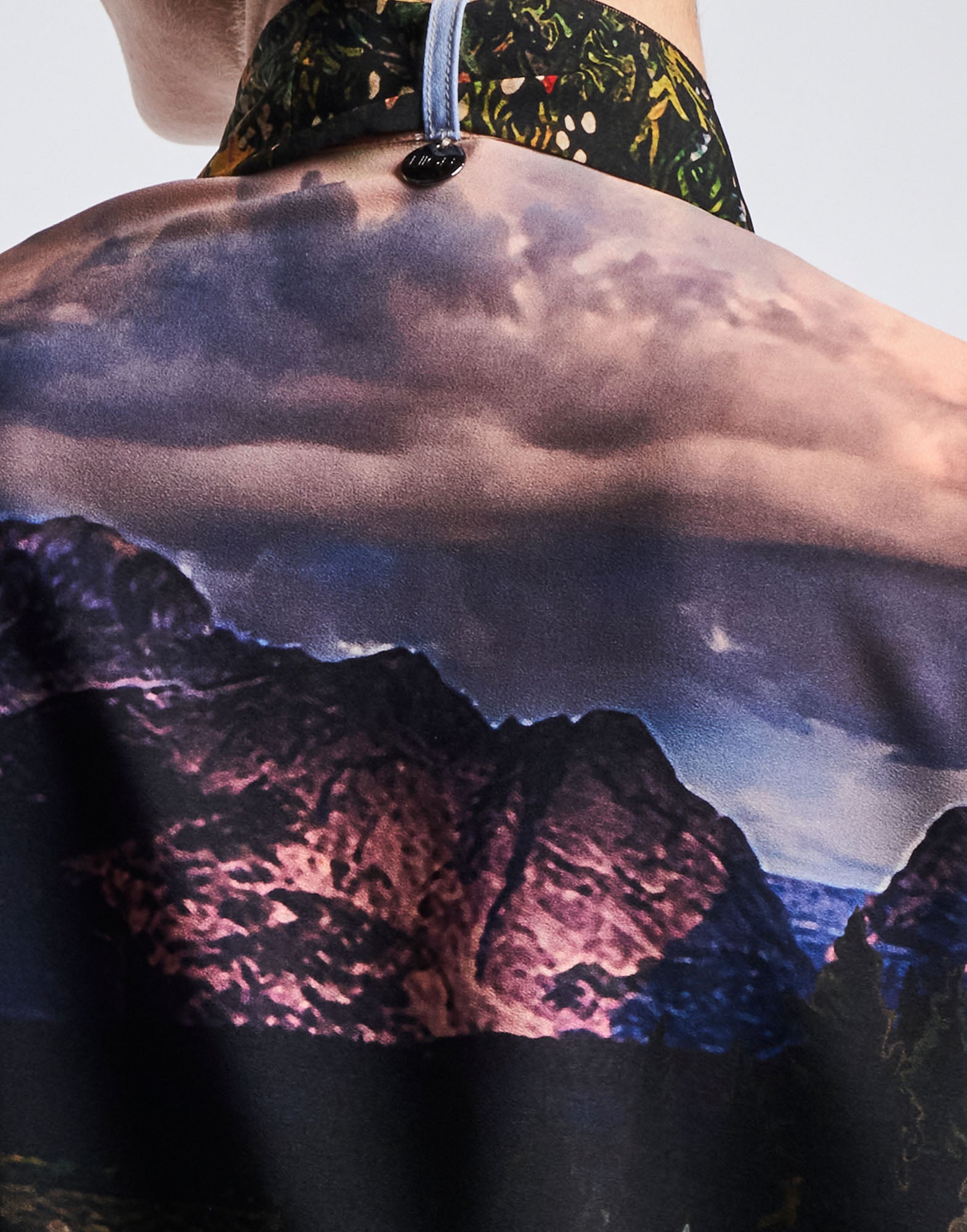 Close-up view of AMAZEMENT shows the stand collar with button closure and colorful 'Wyoming' print on functional crepe, photographed from the back.