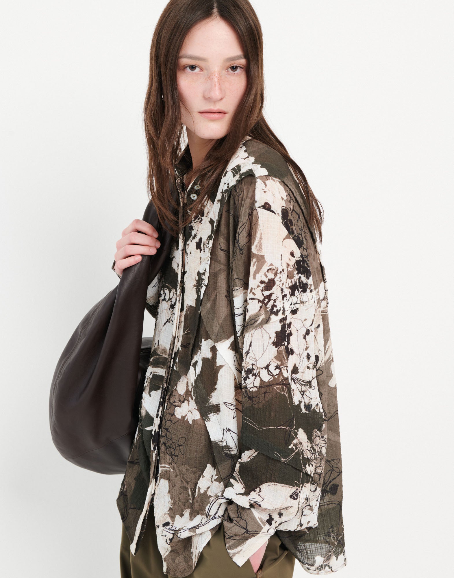 Frontalansicht: Model trägt das oversized Hemd WARRANT mit grün-khakifarbenem Layered Flowers-Muster sowie langen Ärmeln und klassischem Umlegekragen.