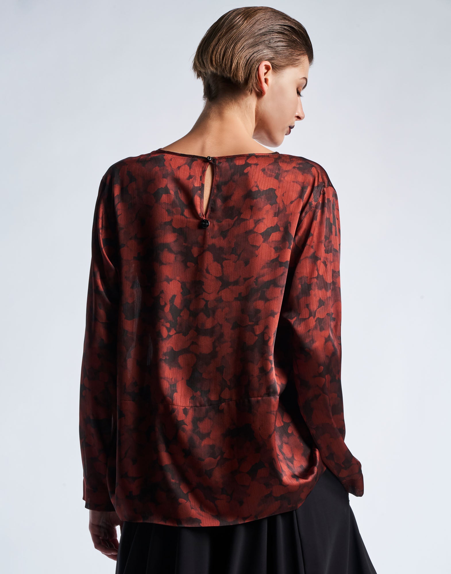 Rückansicht des ALONE Tops aus technischem Krepp im Geo Animalier-Print in Schwarz und Burgunderrot, mit Tropfenöffnung und Knopf am oberen Rücken.