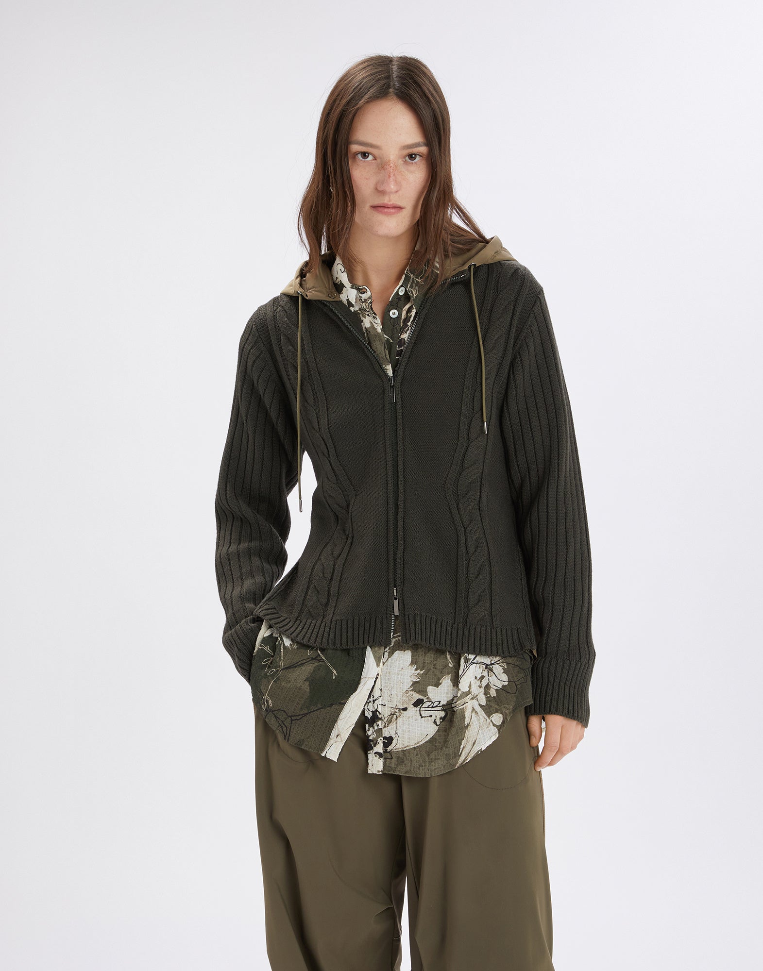 Frontalansicht einer Person, die die FREIZE Strickjacke mit Zopf- und Rippenmuster, Nylon-Kapuze, Frontreißverschluss und seitlichen Reißverschlüssen trägt.