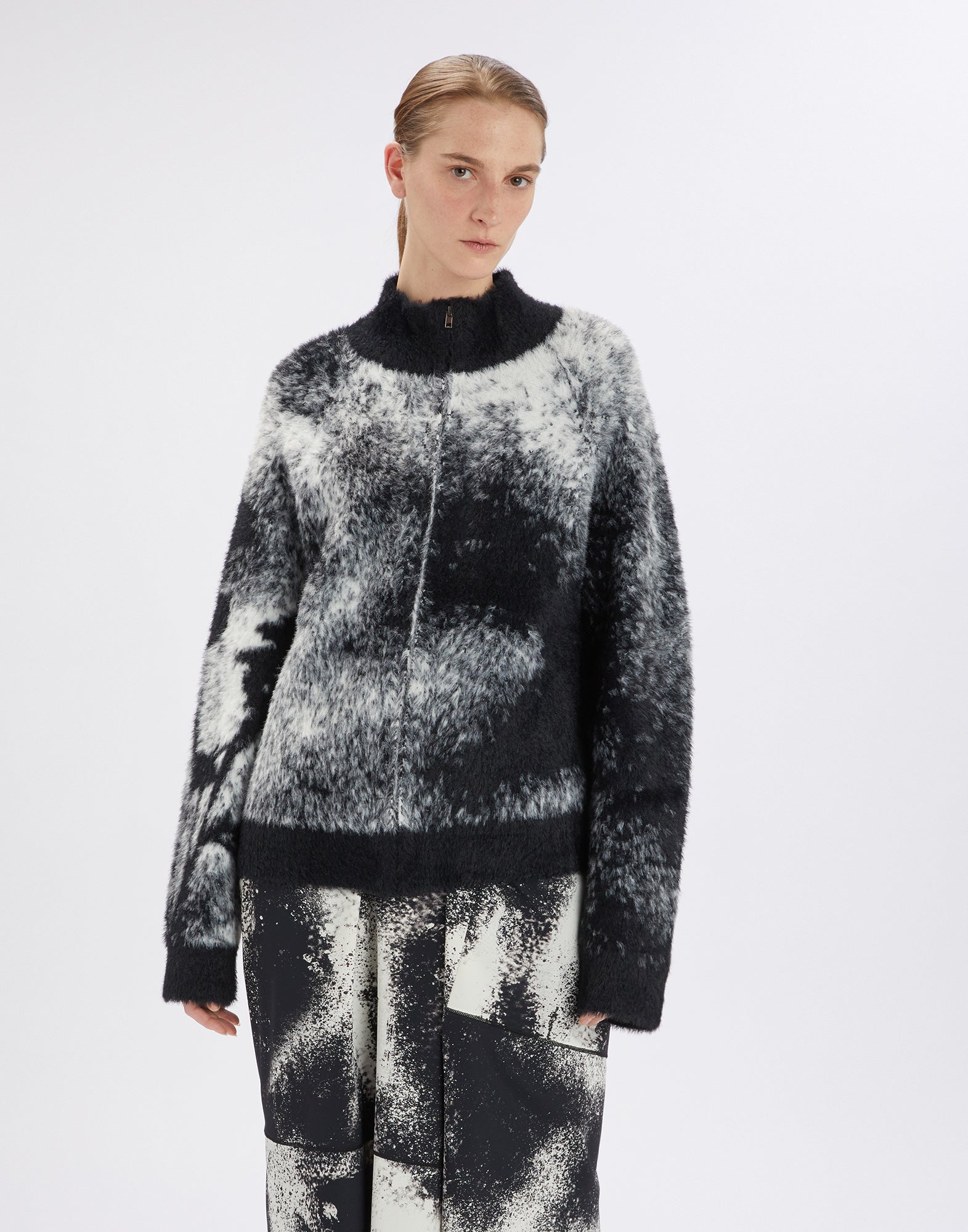 Frontalansicht einer Frau, die den SUMMON UP Cardigan trägt, oversized geschnitten, bicolor Jacquard-Optik mit floralem Muster am rechten Ärmel.