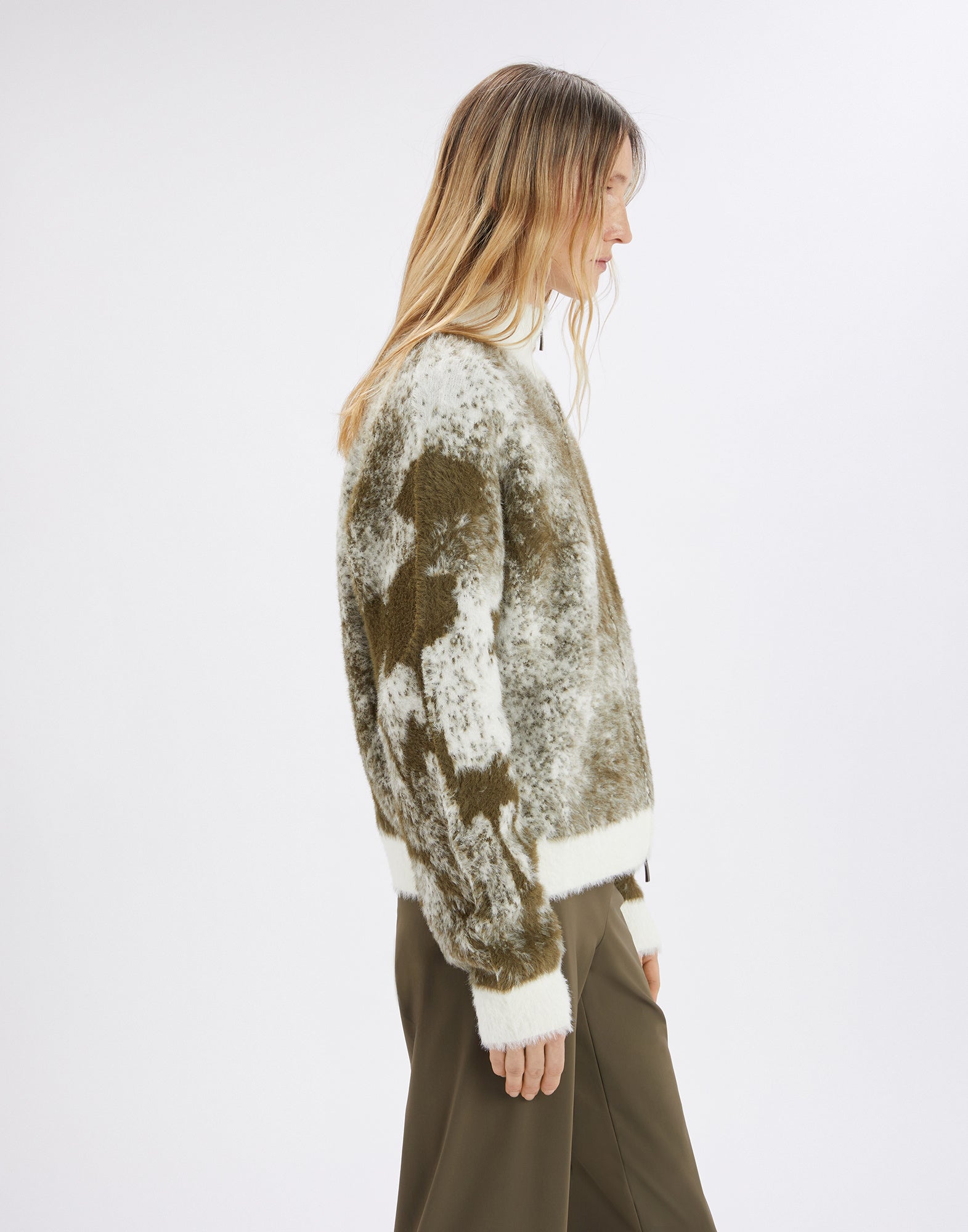 Seitenansicht: Modell trägt den SUMMON UP Cardigan in bicolor Jacquard mit floralem Muster am rechten Ärmel, Stehkragen und unifarbenen Bündchen.